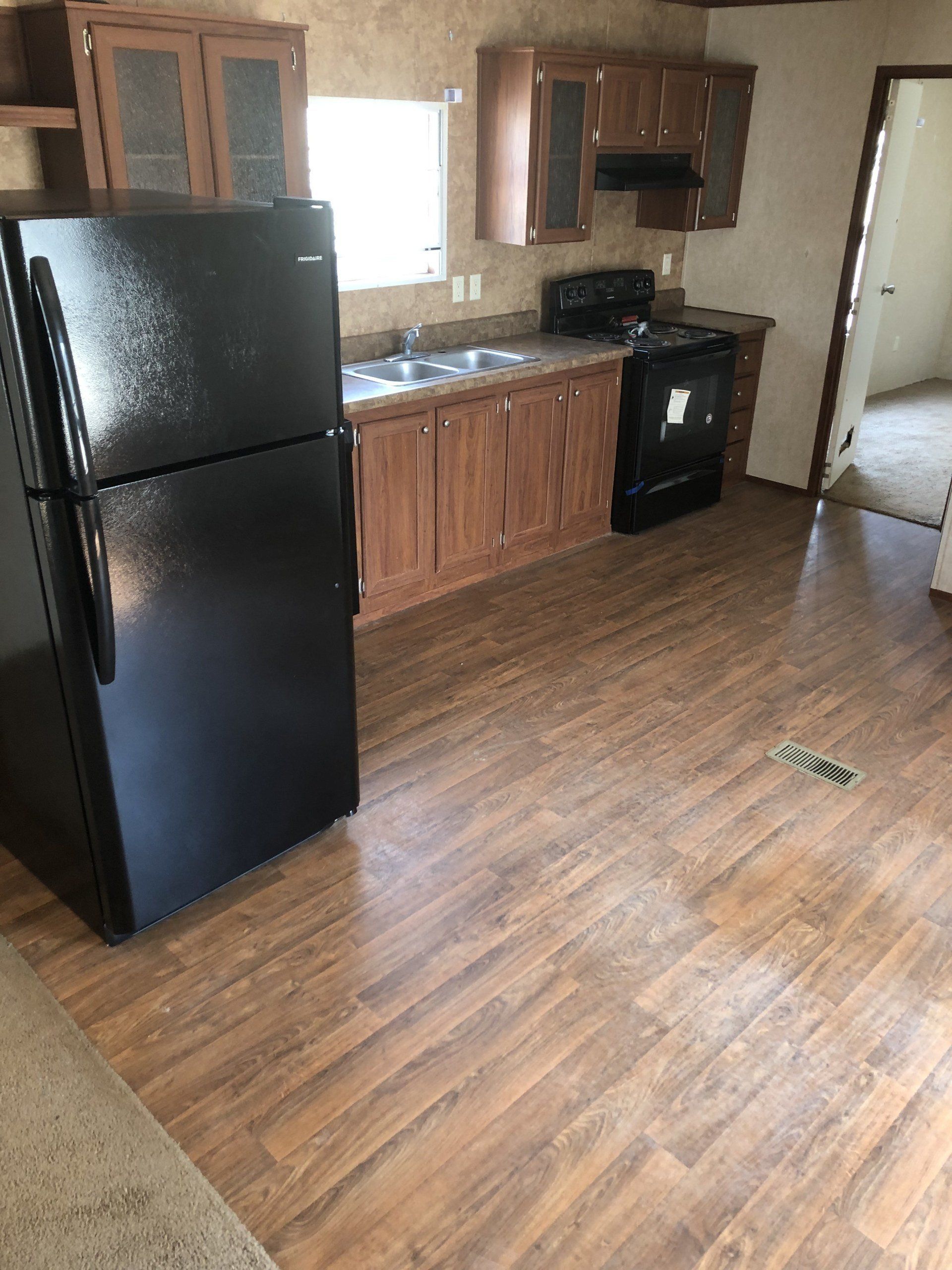 A kitchen with a black refrigerator, stove, sink and cabinets
