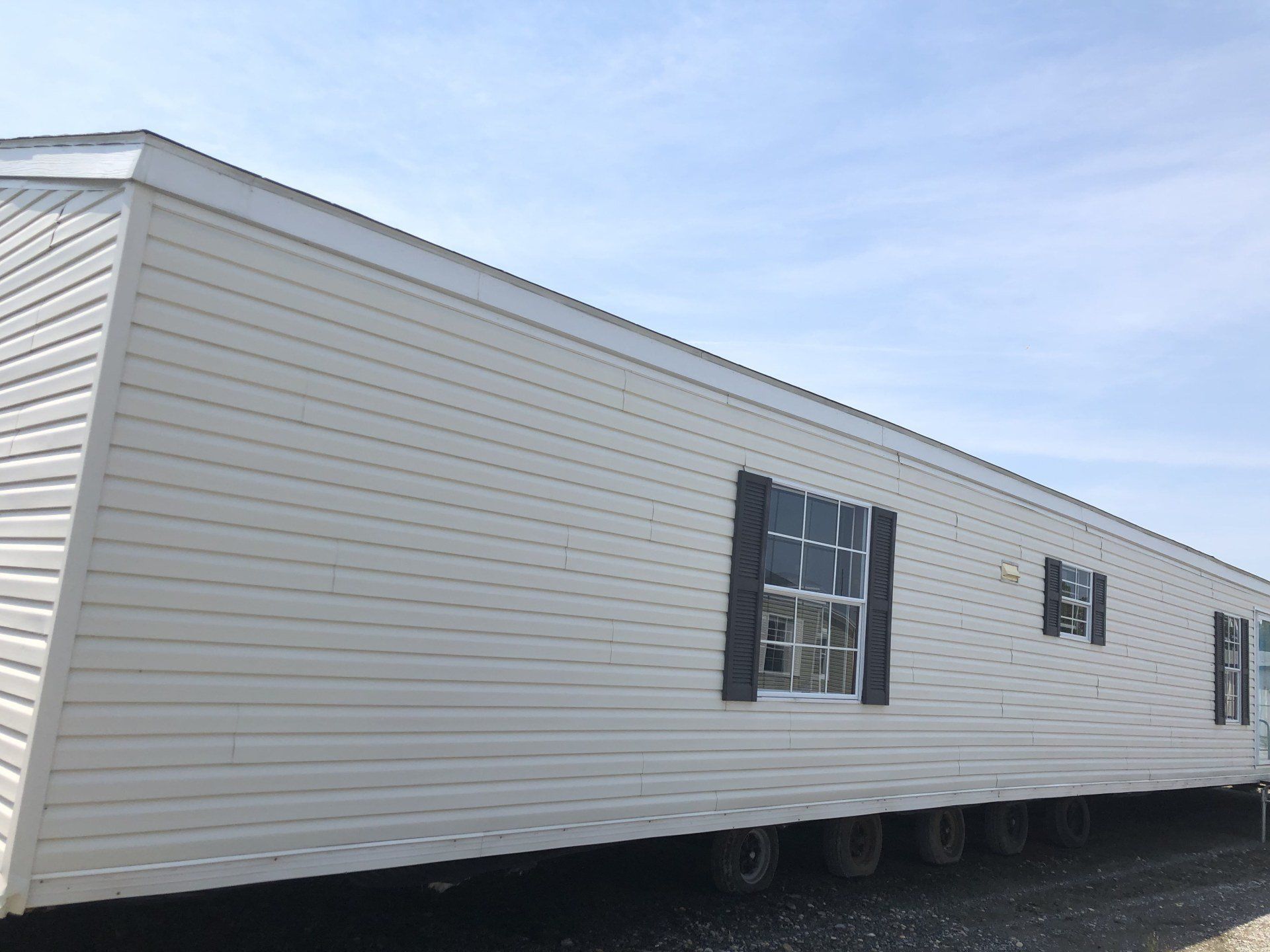 A white mobile home with black shutters is parked on the side of the road