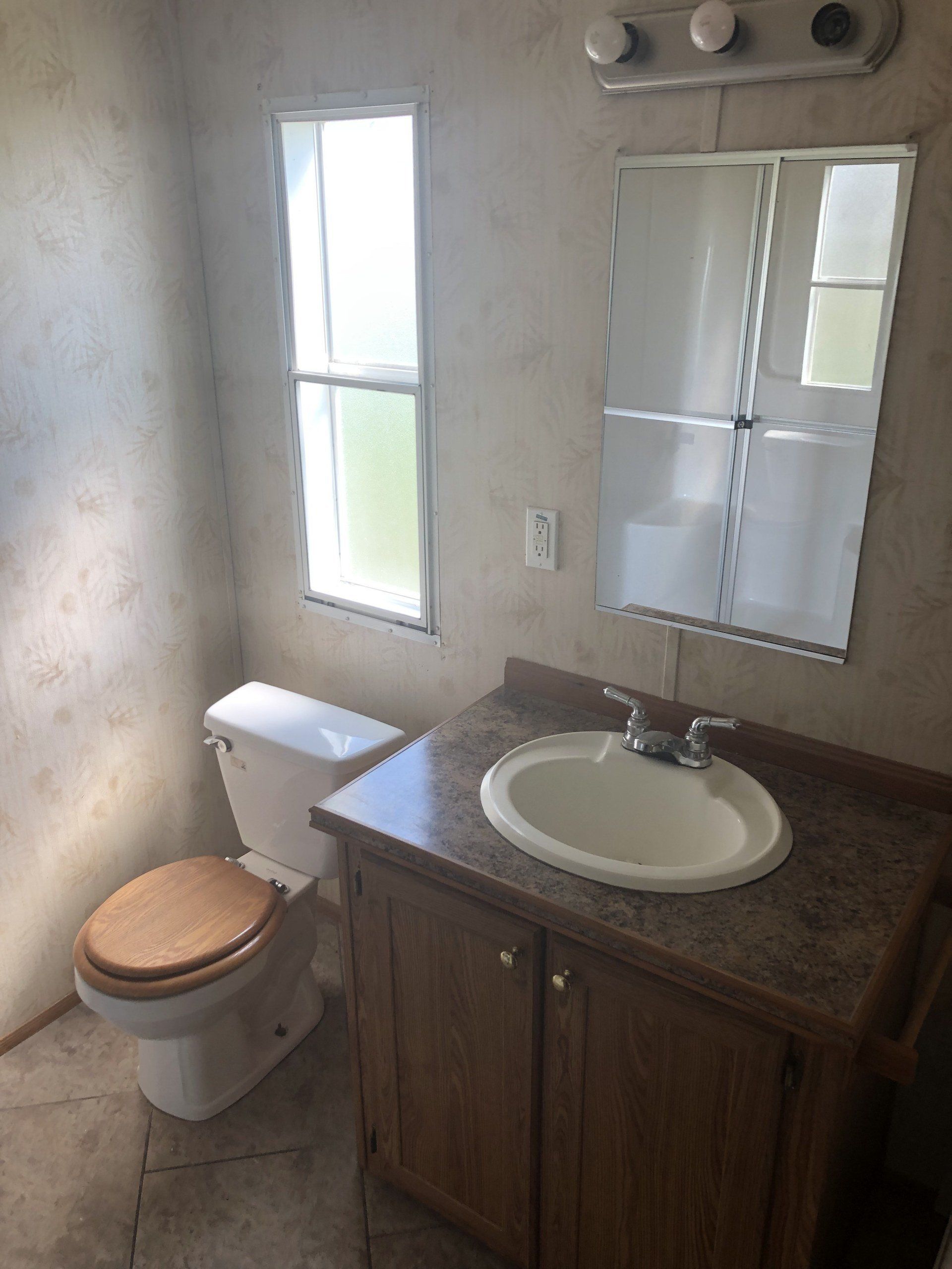 A bathroom with a toilet, sink and mirror
