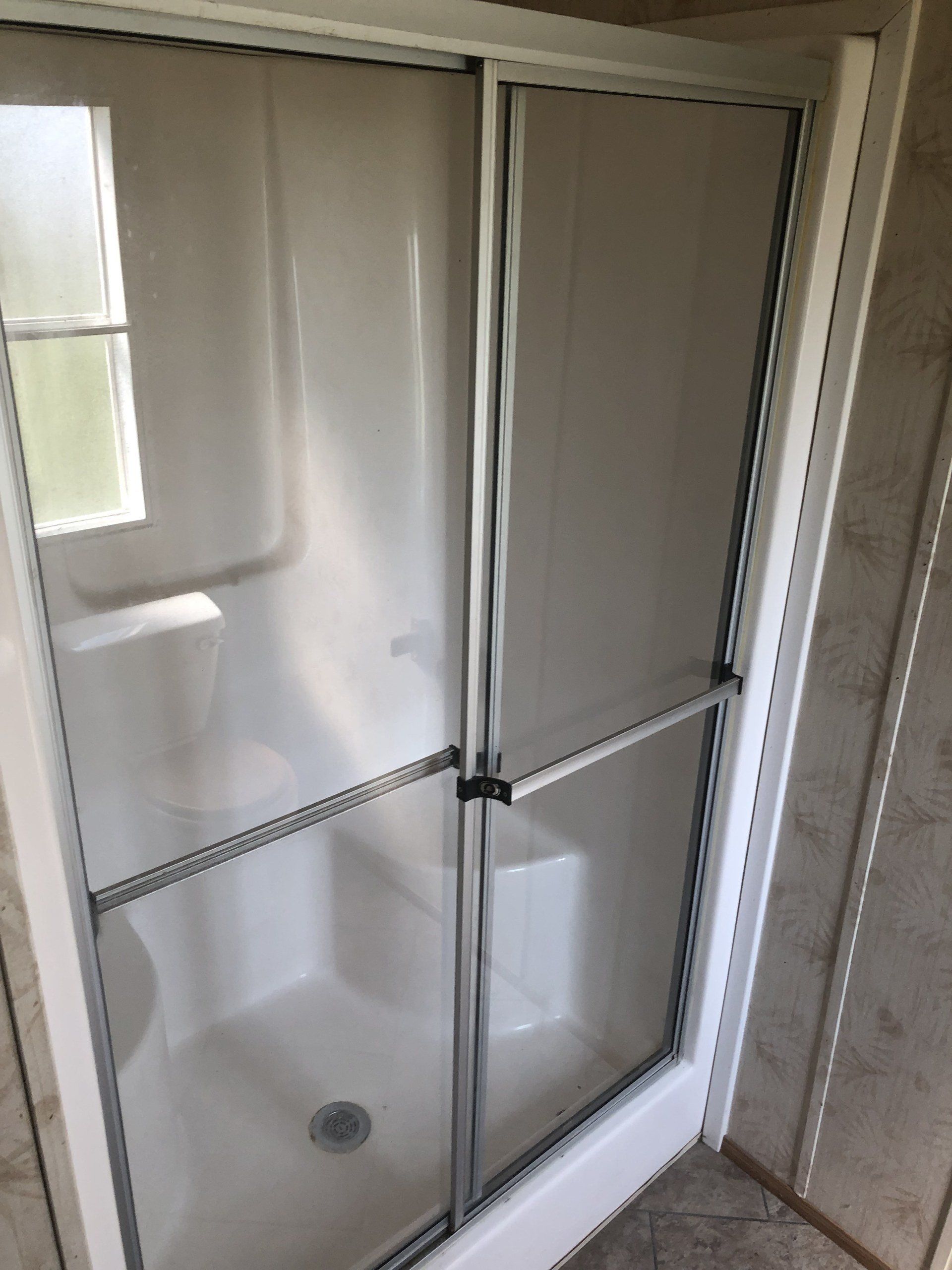 A shower stall with sliding glass doors in a bathroom