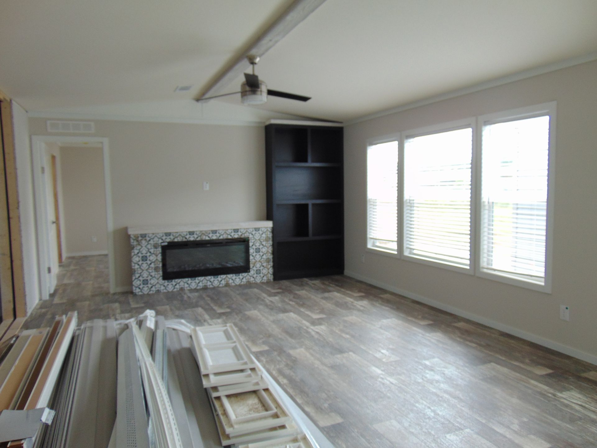 an empty living room with a fireplace and a ceiling fan