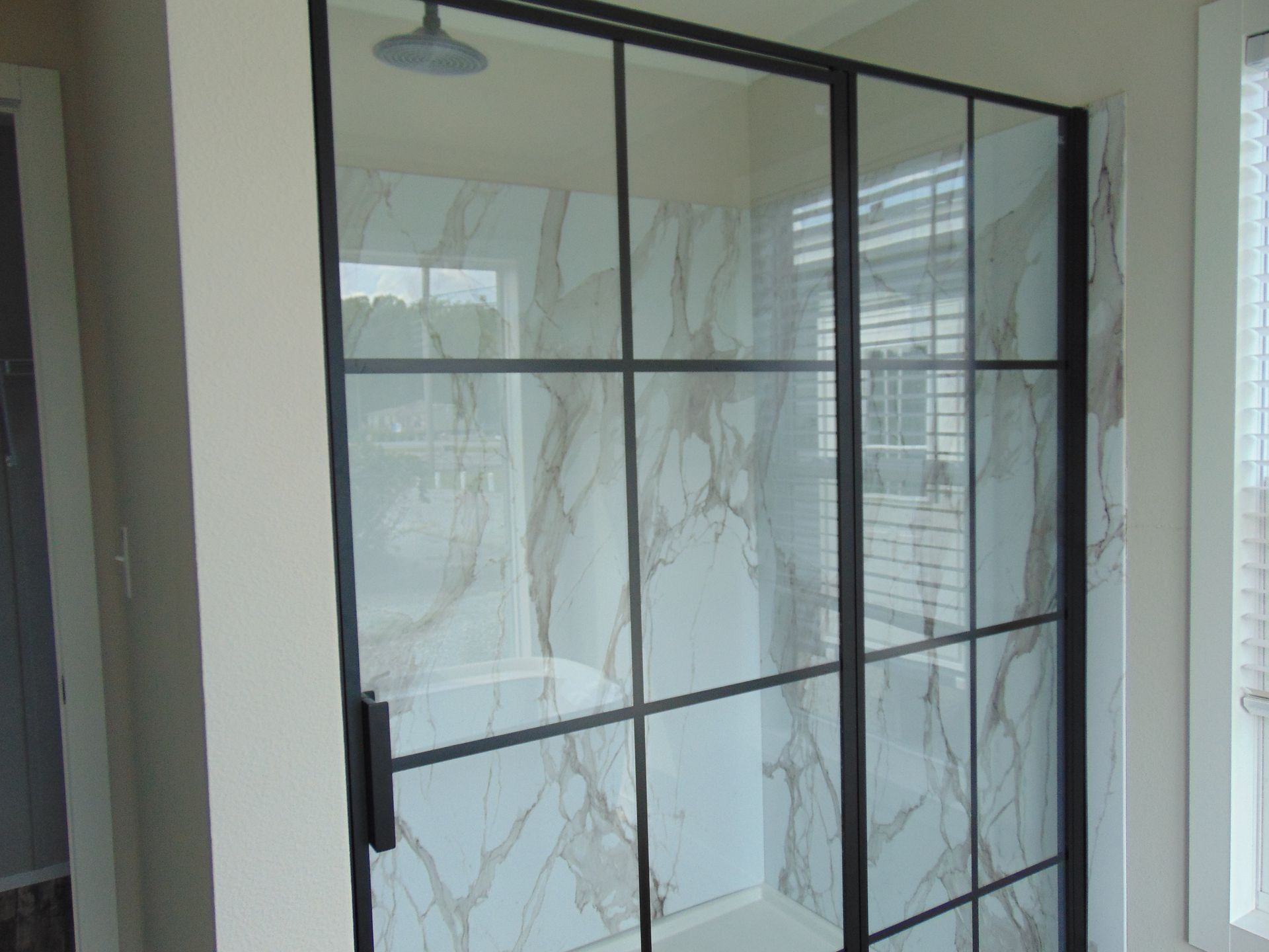 a bathroom with a glass shower door and marble walls