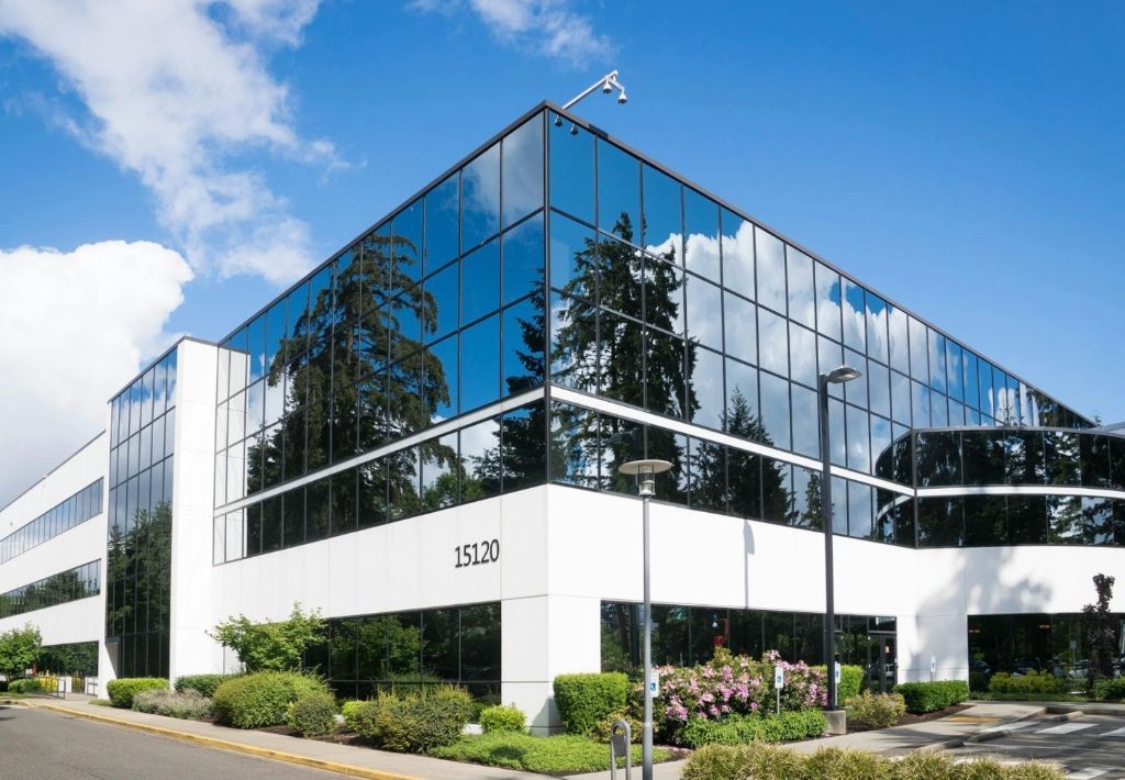 Modern office building with glass windows reflecting the sky and trees, number 15130 visible.