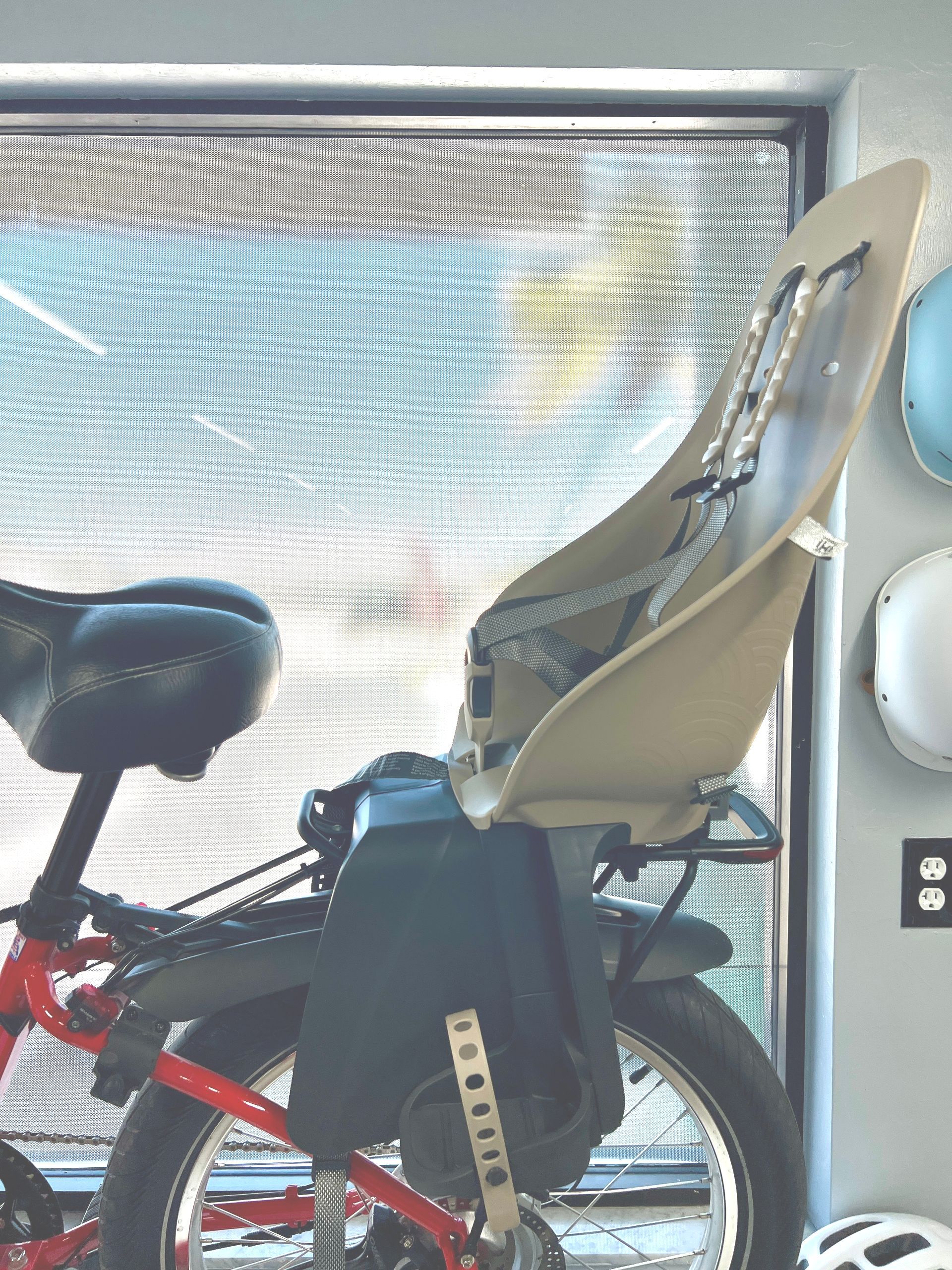 A bicycle with a baby seat attached to it is parked in front of a window.