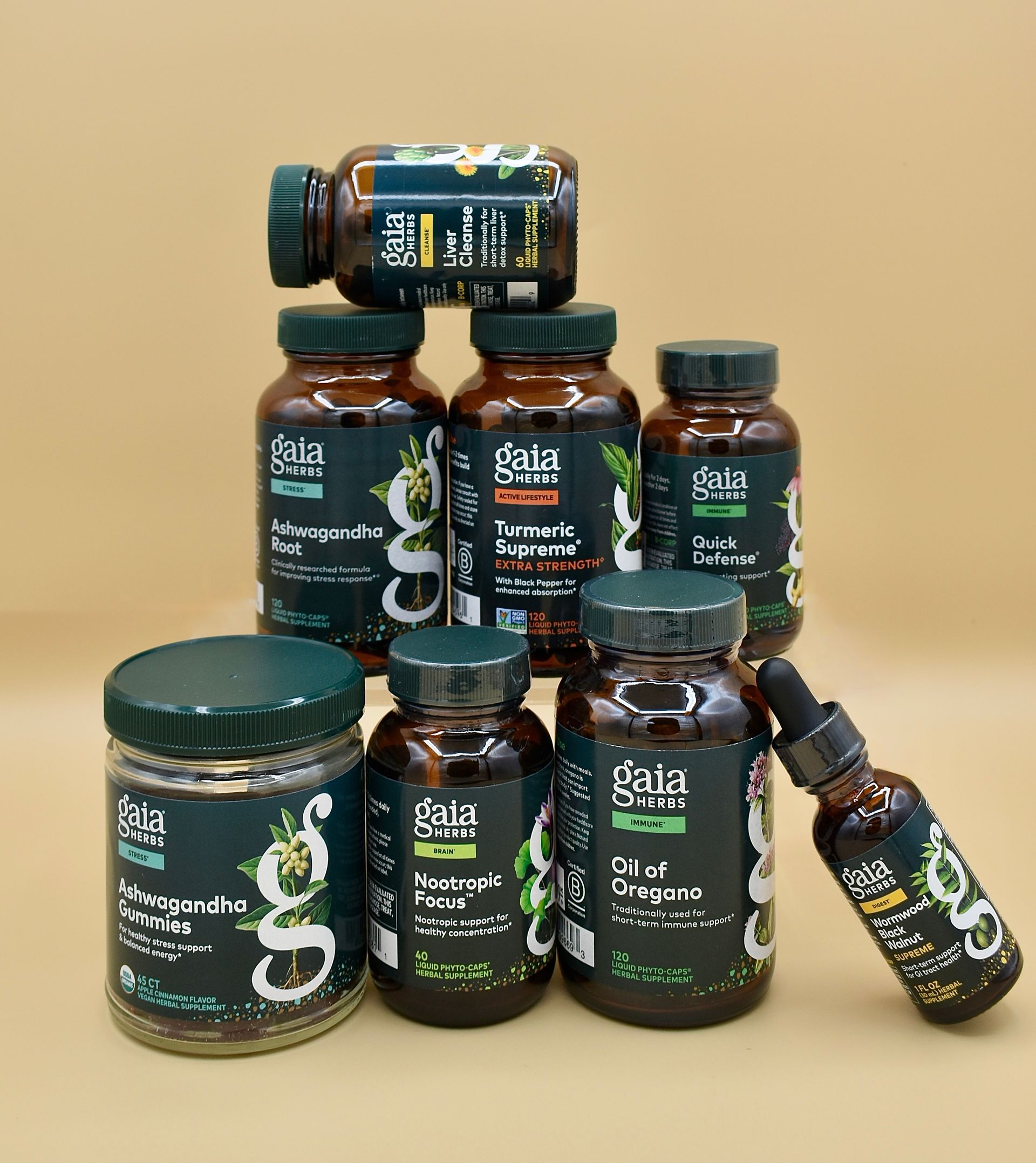 Assorted dark glass jars and bottles with green labels stacked on a beige background
