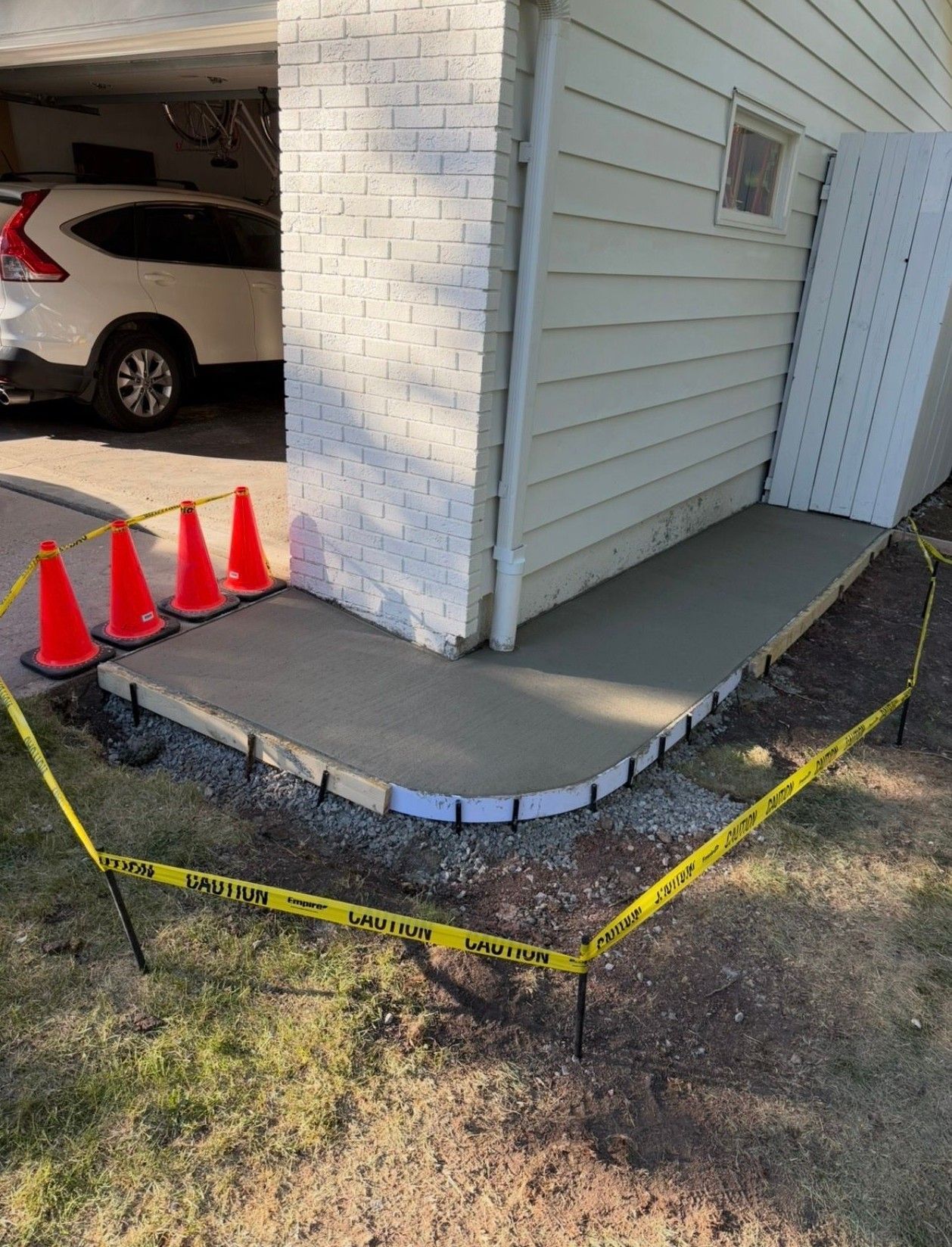 Accessible ramp beside a building entrance, with cones and yellow caution tape around the curved concrete edge.