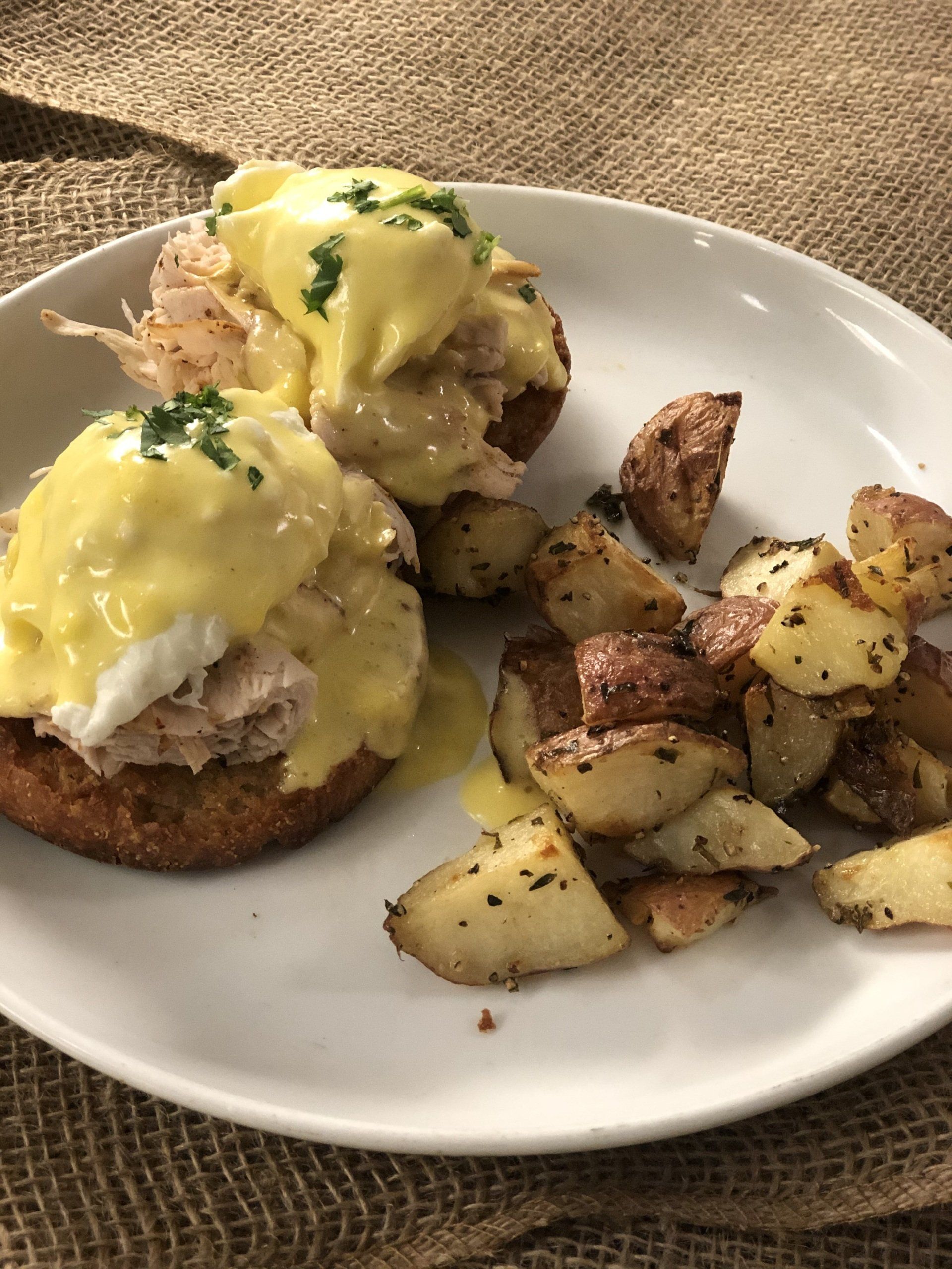 A white plate topped with a sandwich and potatoes on a table.