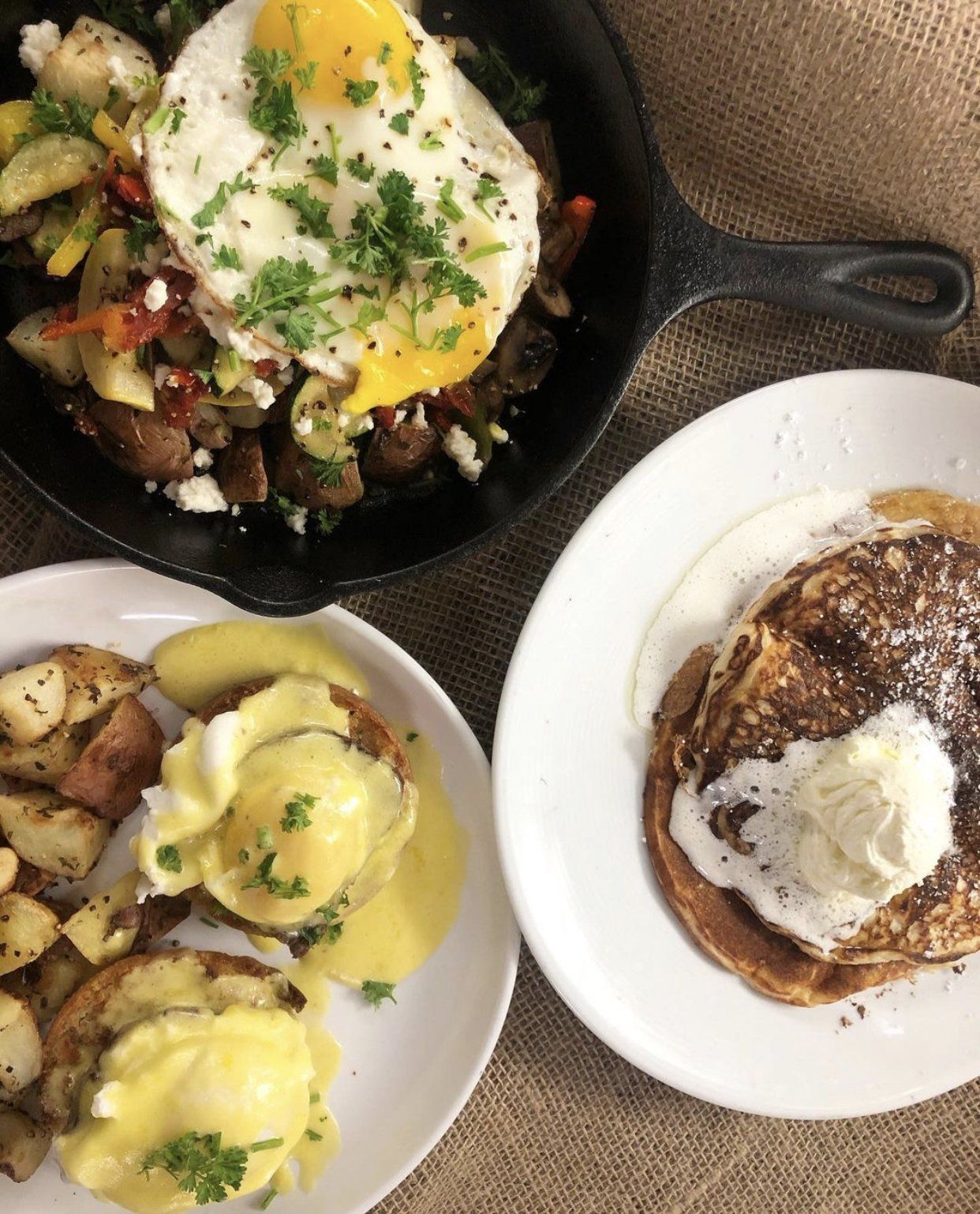 Three plates of food on a table including pancakes and eggs