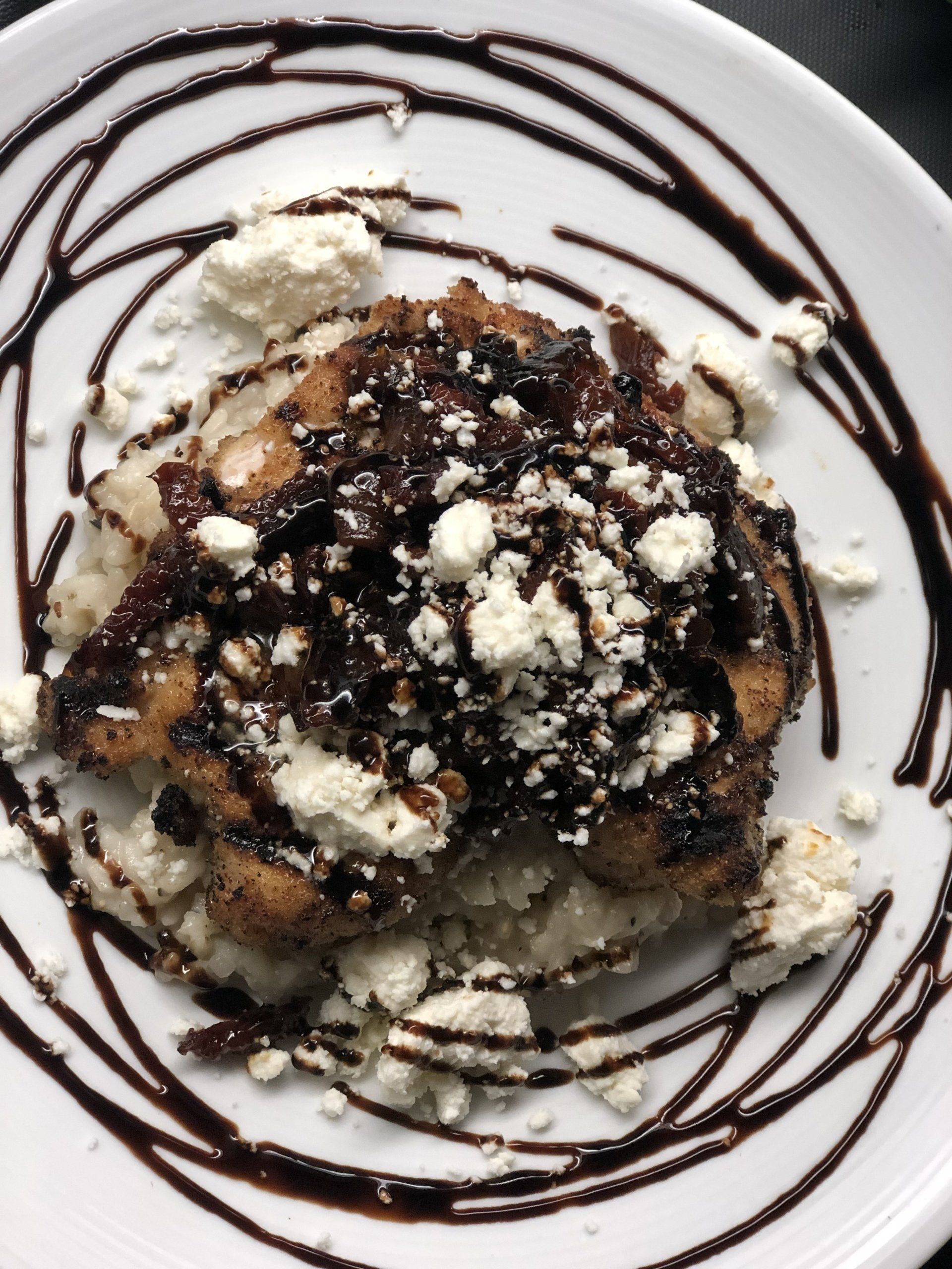 A white plate topped with food and chocolate sauce