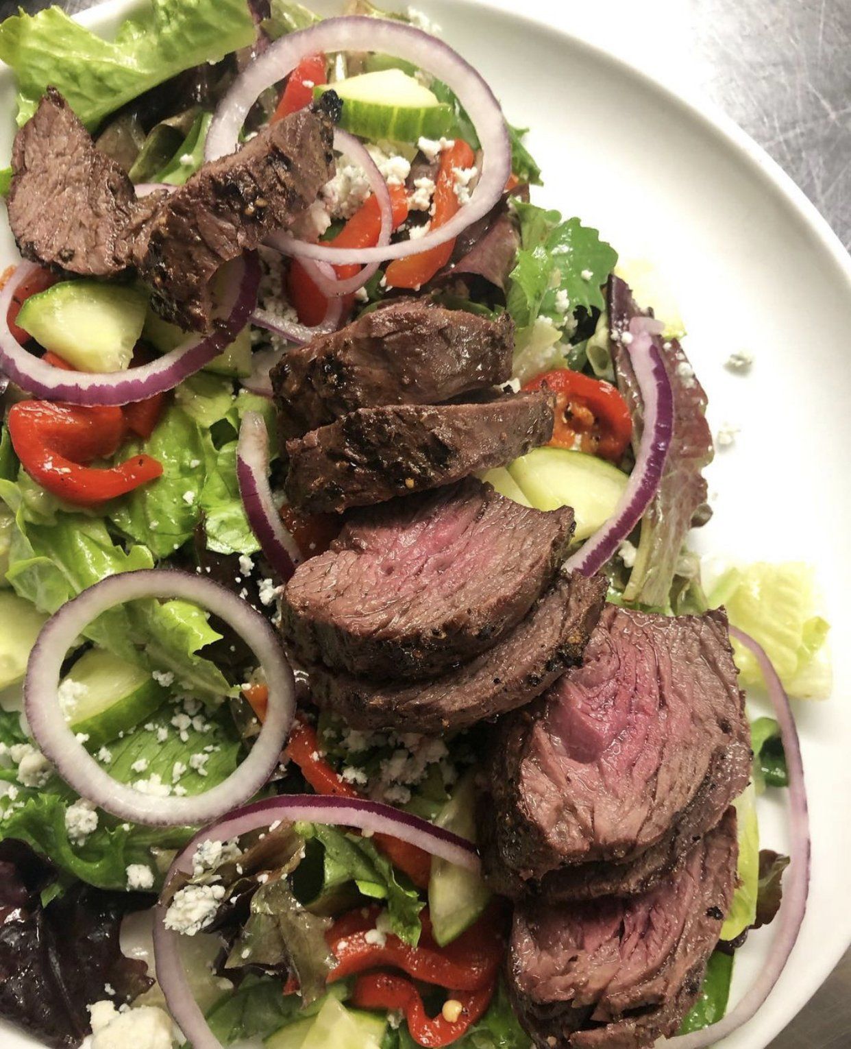 A close up of a salad with meat and vegetables on a plate