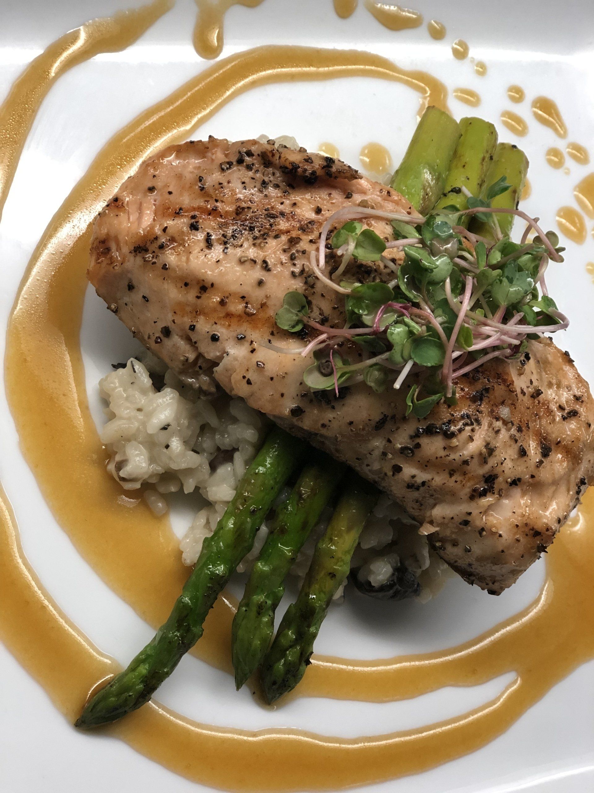 A white plate topped with a piece of meat and asparagus