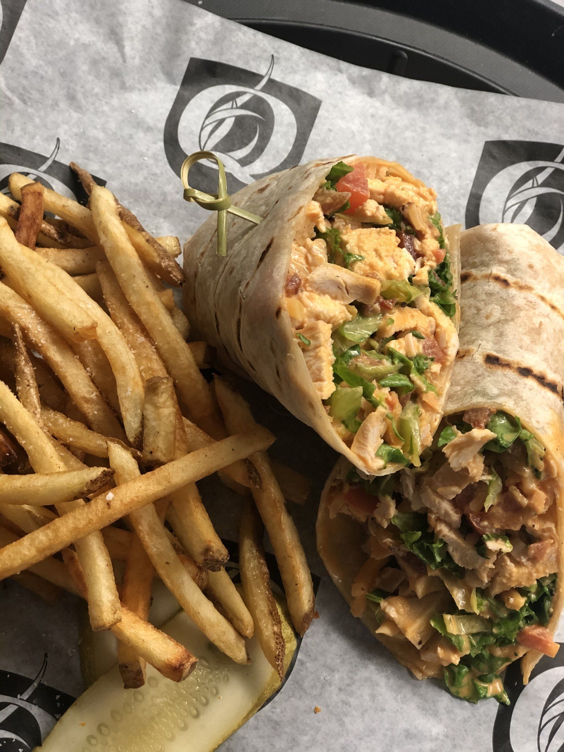 A close up of a wrap and french fries on a tray