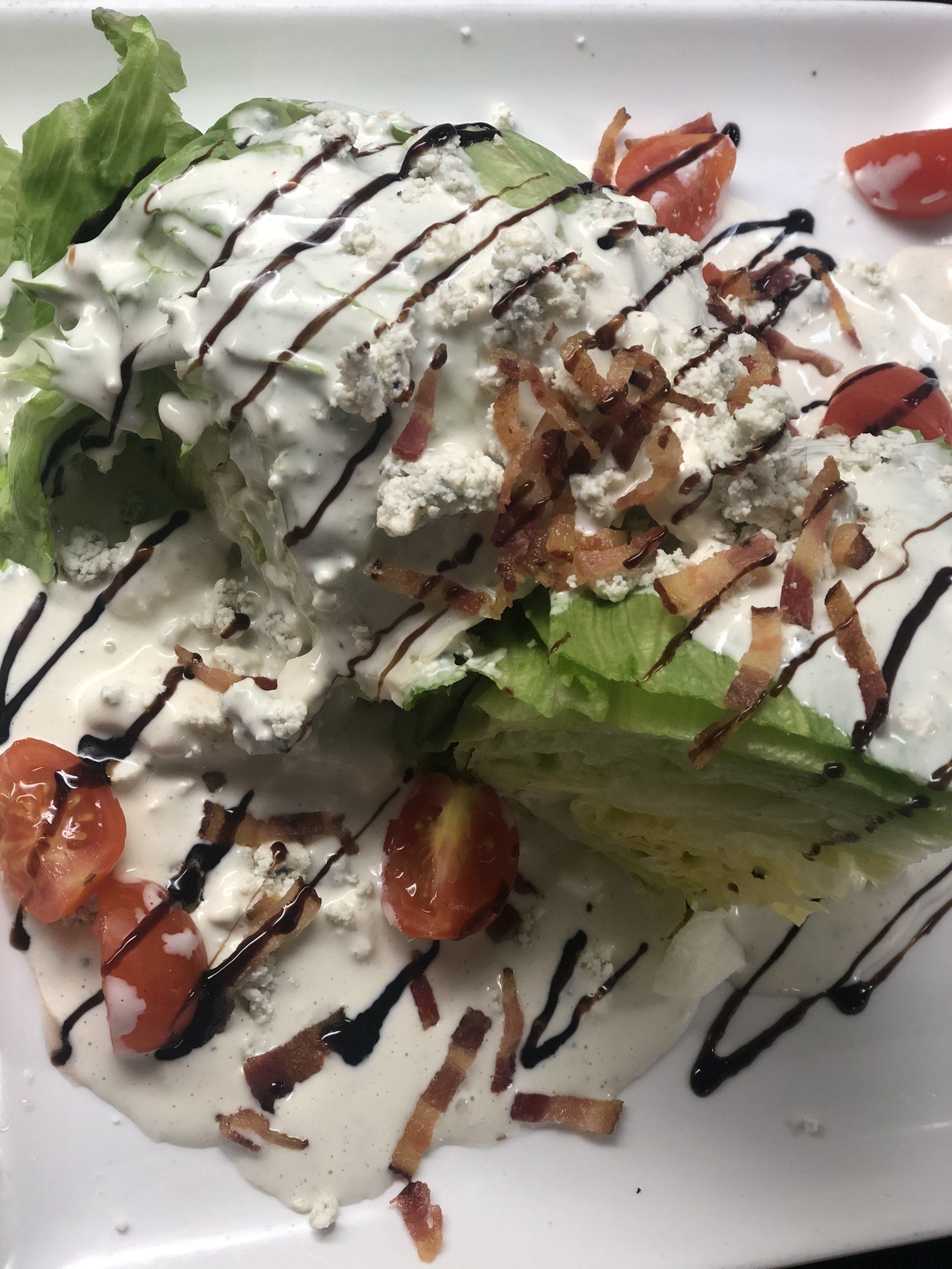 A salad with lettuce tomatoes and bacon on a white plate