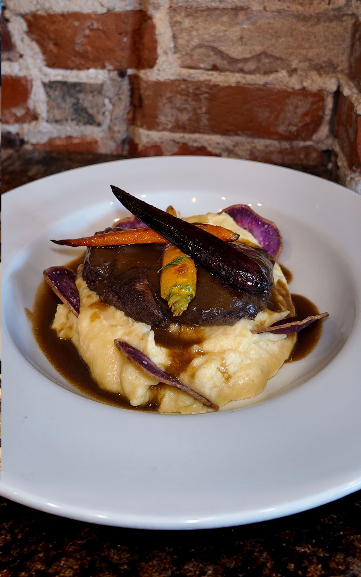 Plated gourmet dish with creamy mash, sauce, and garnish on a white plate