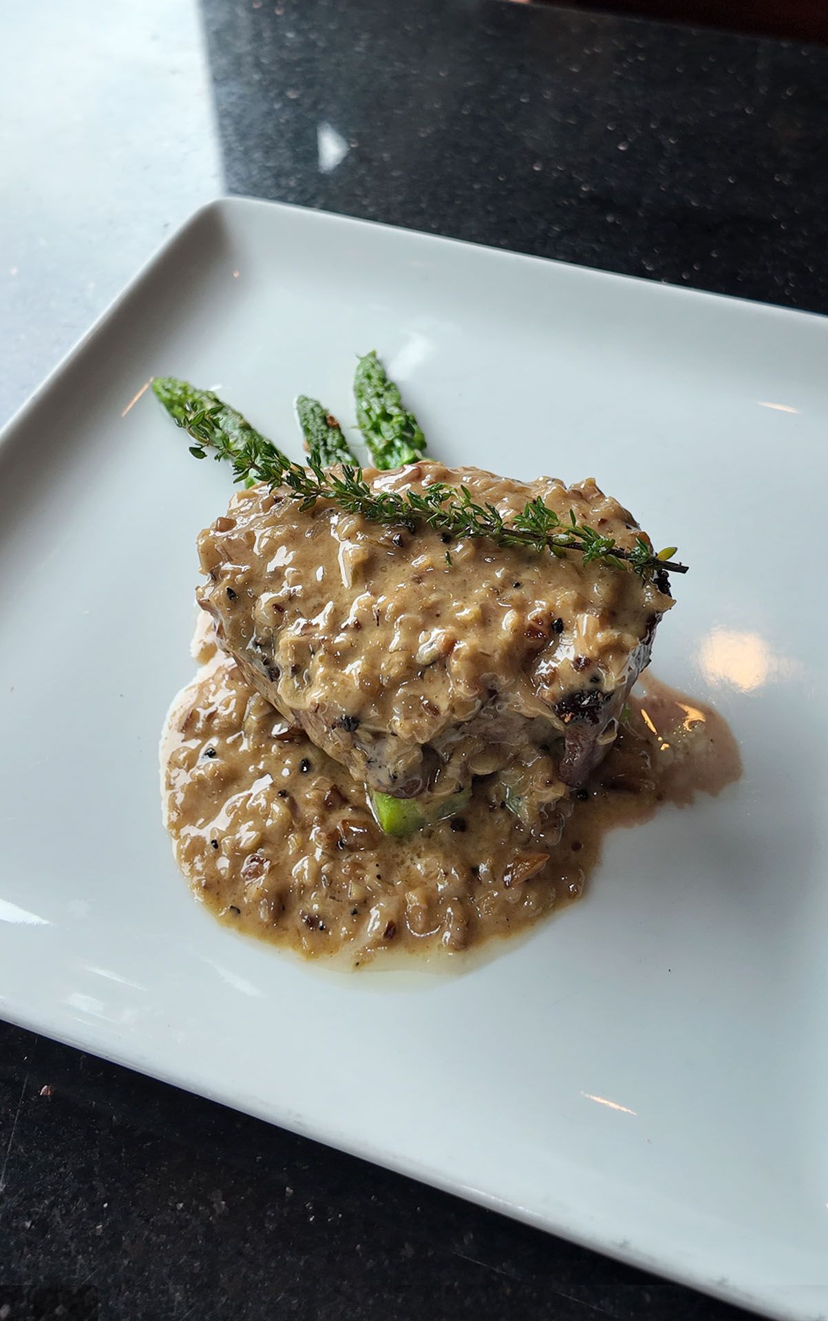 Creamy risotto topped with asparagus spears on a white plate