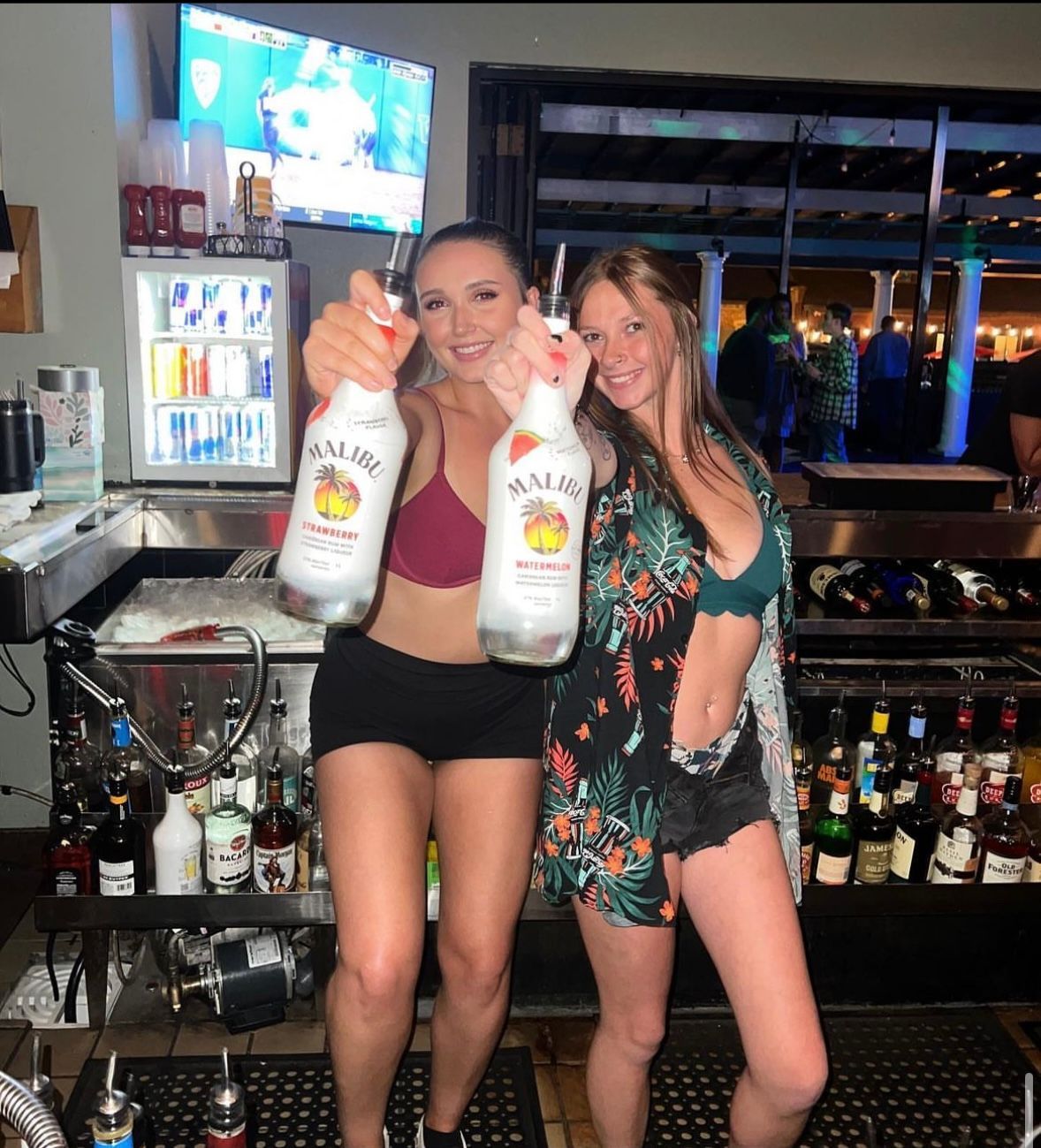 two girls in a bar holding liquor