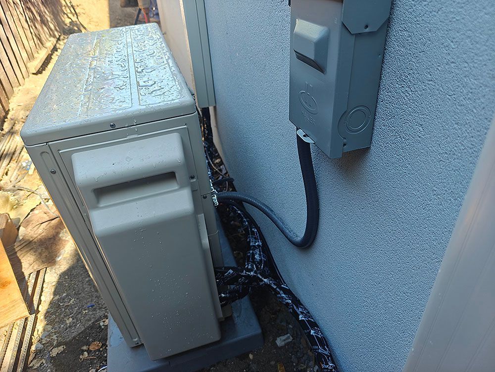 Outdoor air conditioning unit with electrical conduit on a stucco wall.
