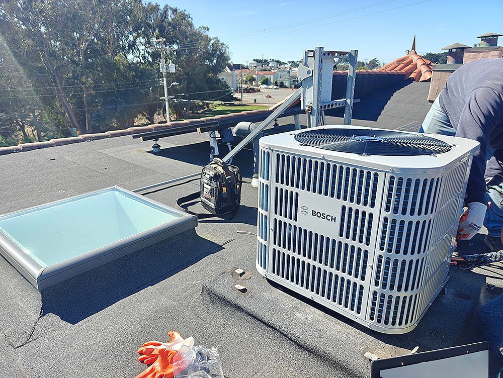HVAC unit on a rooftop next to a skylight and a person. Sunny day.