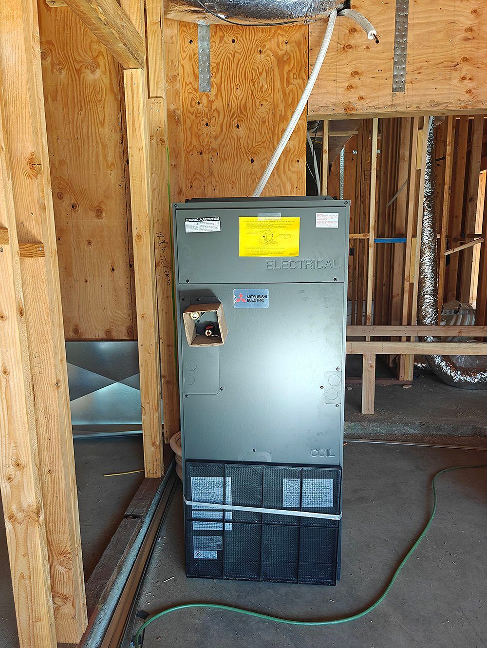 HVAC unit in a wooden-framed building. The unit is gray with a yellow sticker.