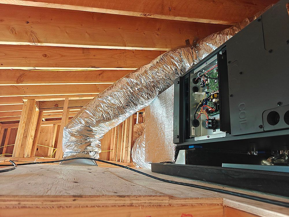 HVAC unit with flexible ductwork in an unfinished attic space. Wooden framing is visible.