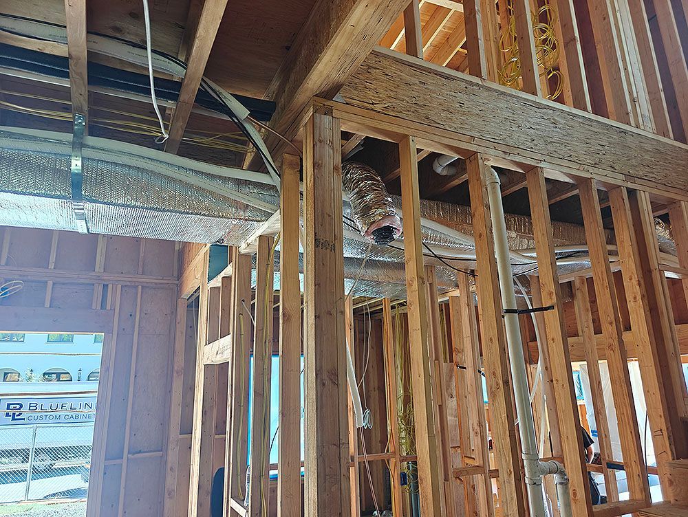 Interior of a building under construction. Wooden framing with ductwork and insulation visible.