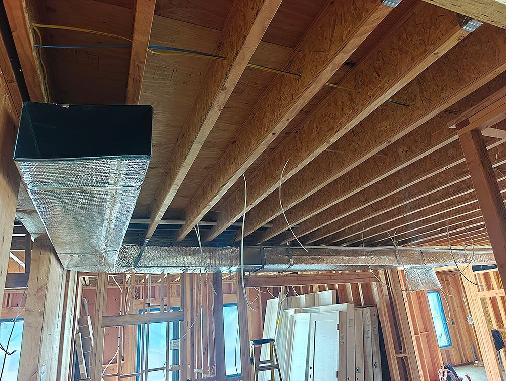 Wooden beams with silver ductwork running through a construction site.