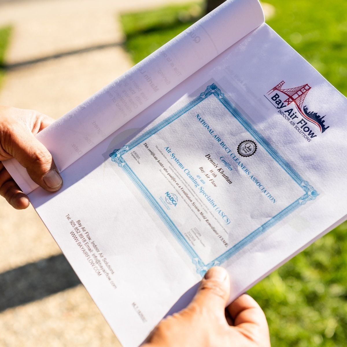 Hands holding a white envelope with a certificate inside, logo.