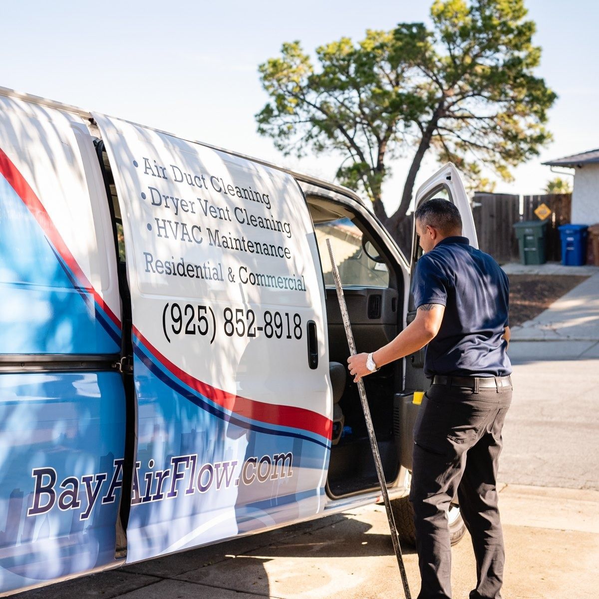 Man exiting a van with air duct cleaning services. The van is white, with text and a logo.