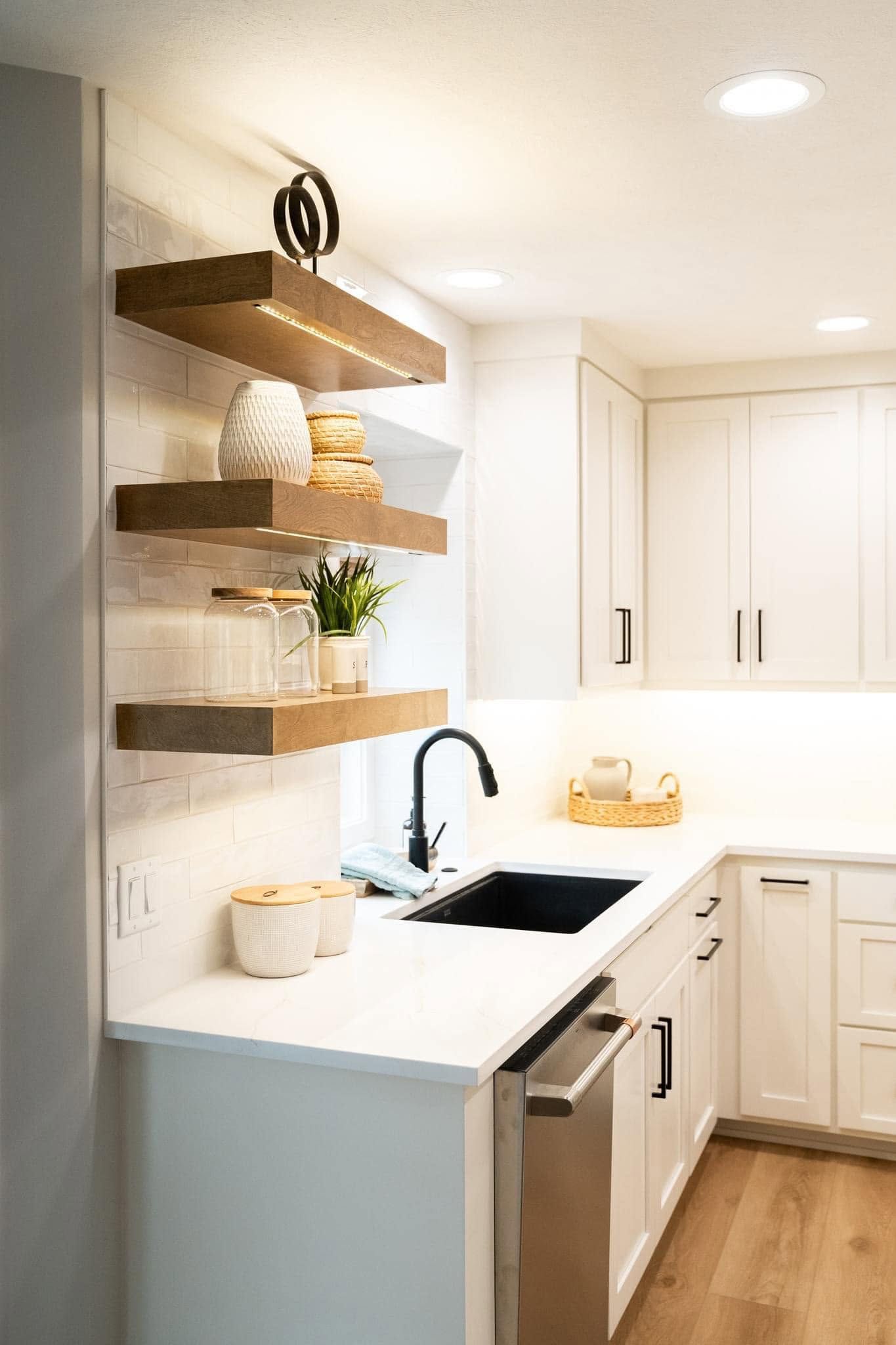 Modern white kitchen with open wood shelves, black faucet, and light wood floor