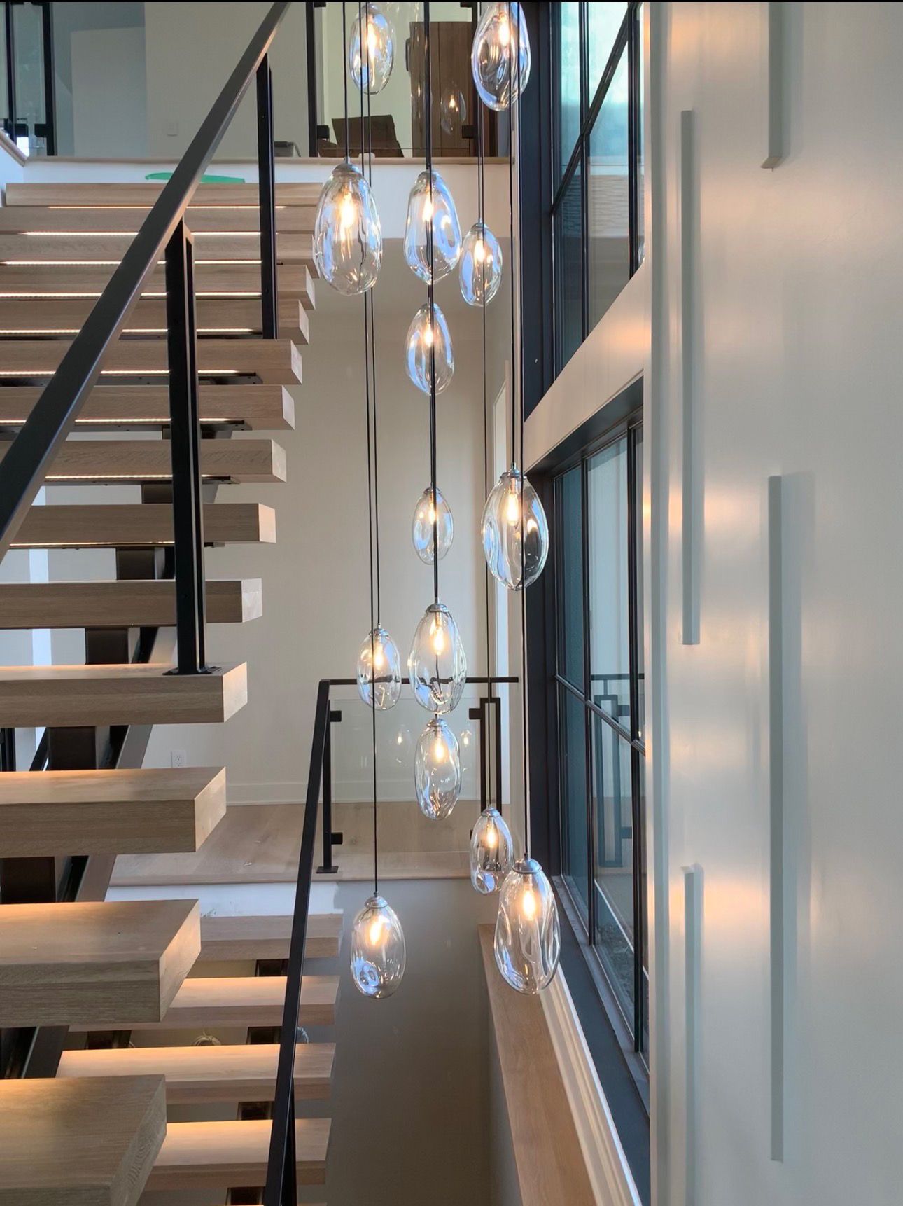 Modern staircase with hanging glass pendant lights in a bright interior hallway