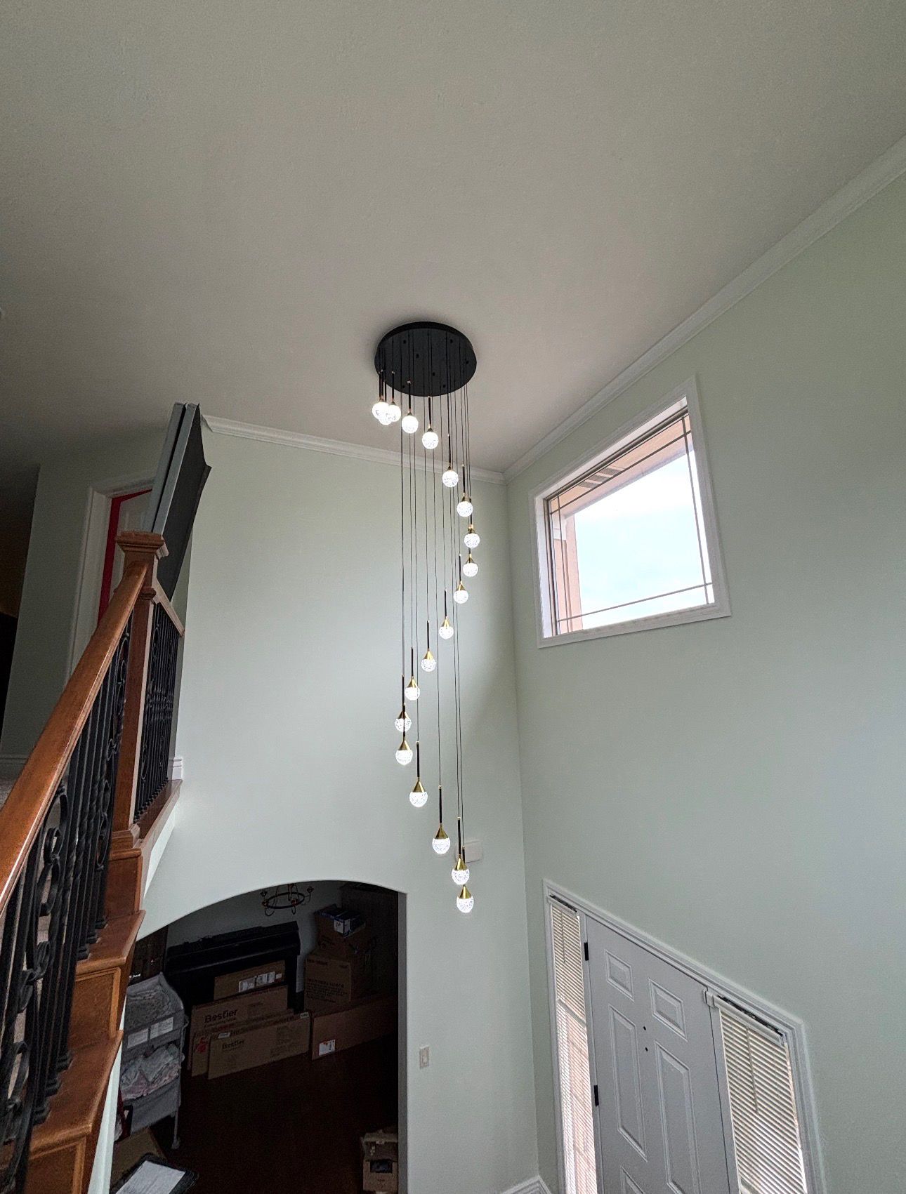 Stairwell with a hanging light fixture, small window, and white walls above a staircase