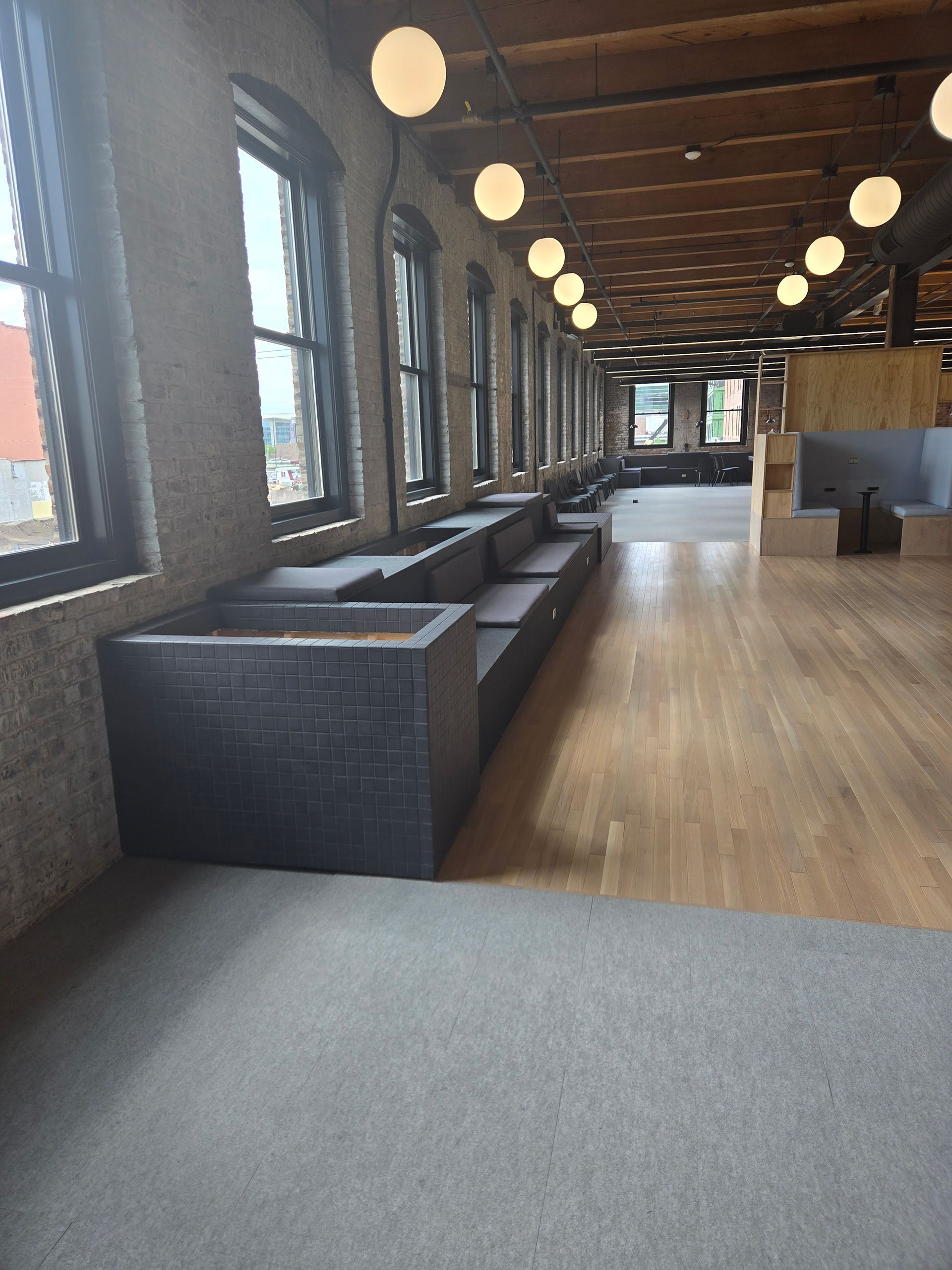 Modern lounge with long windows, wicker sofas, wooden floor, and round pendant lights.