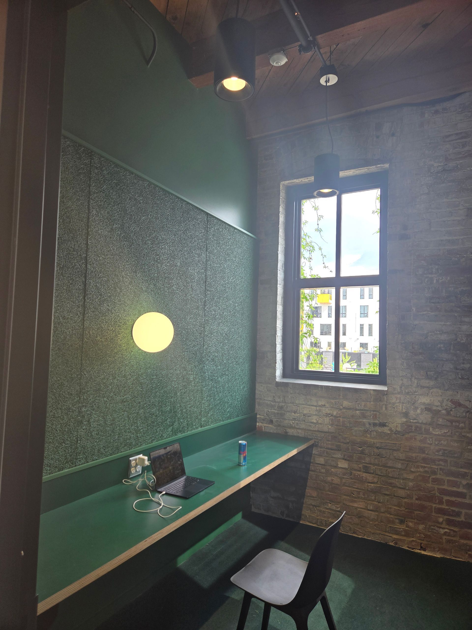 Small cafe seating nook with green walls, a table, chair, and window light.