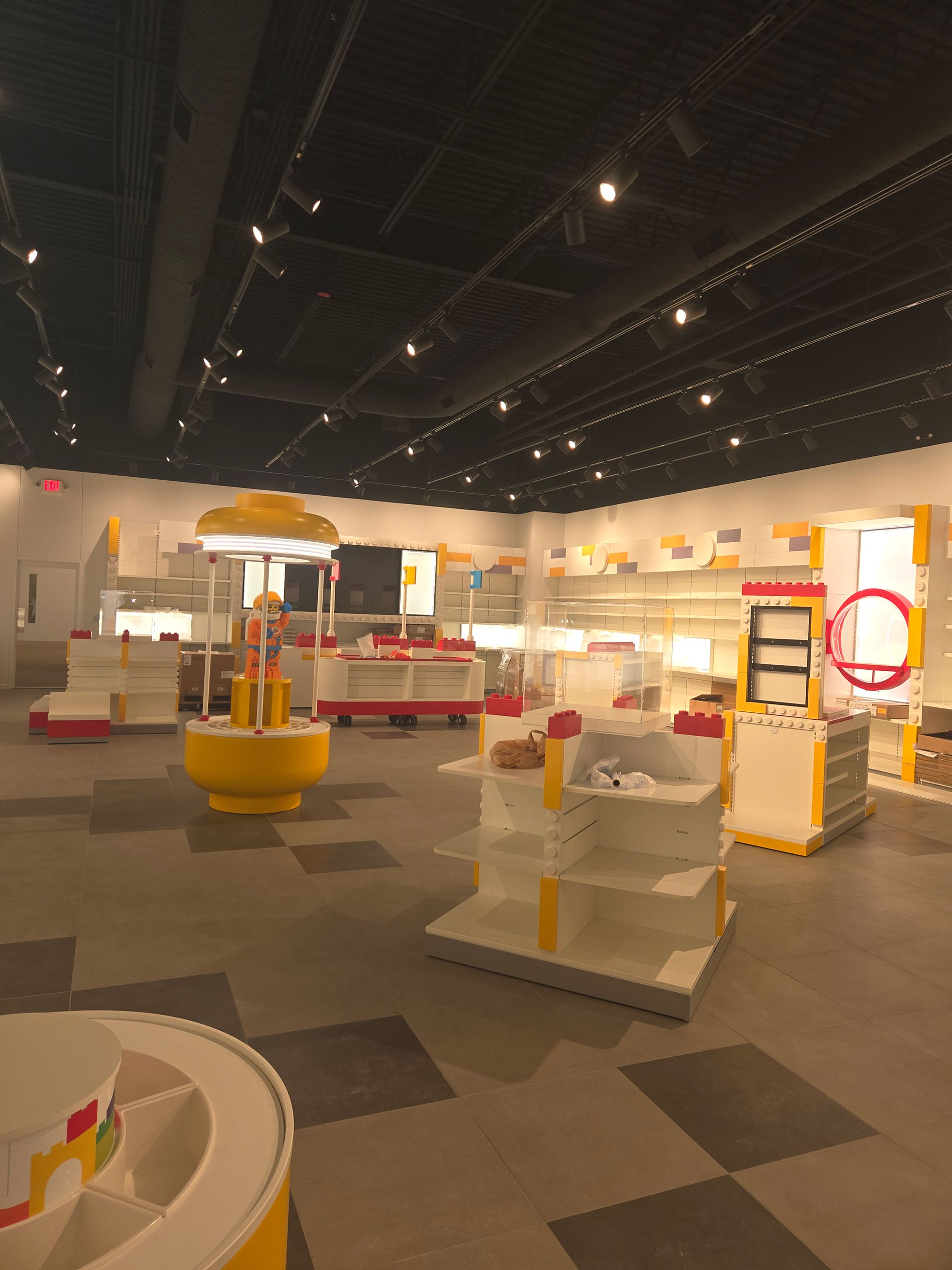 Empty interactive museum exhibit with white and orange display stations under a dark ceiling