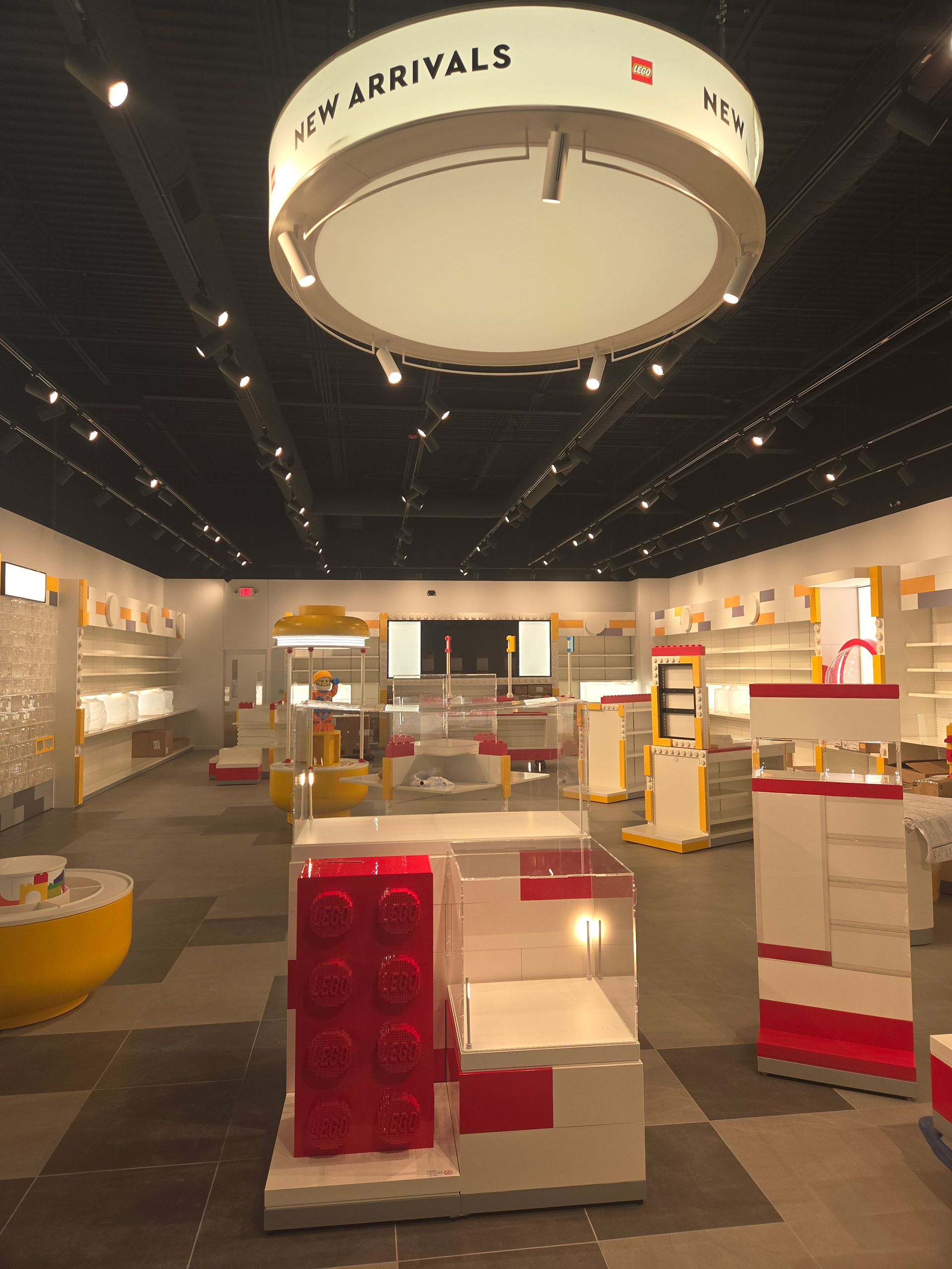Toy airport arrivals area with LEGO-style displays and red-and-white counters under a large ceiling sign