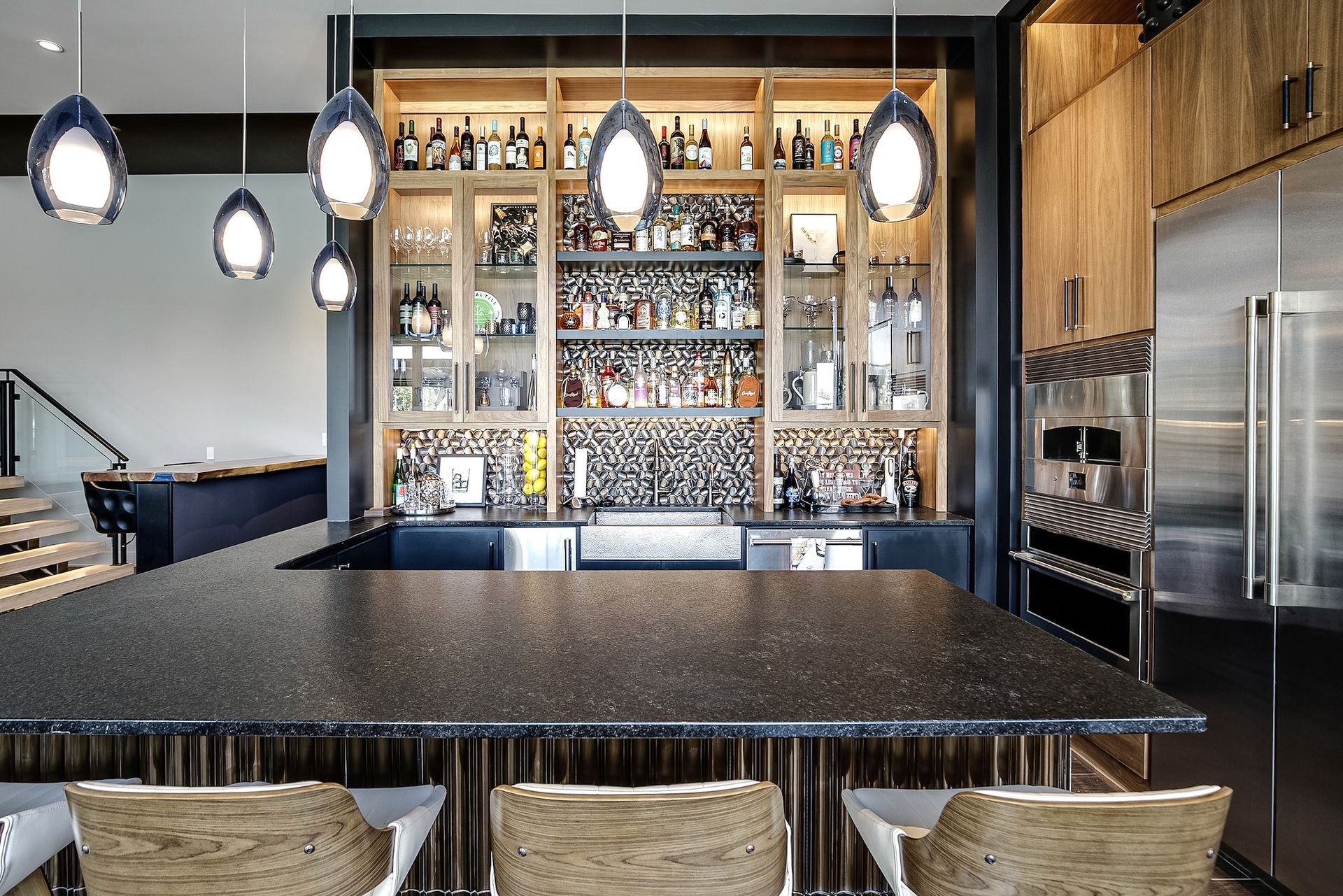 Modern restaurant bar with pendant lights, shelves of bottles, and stools at a long counter