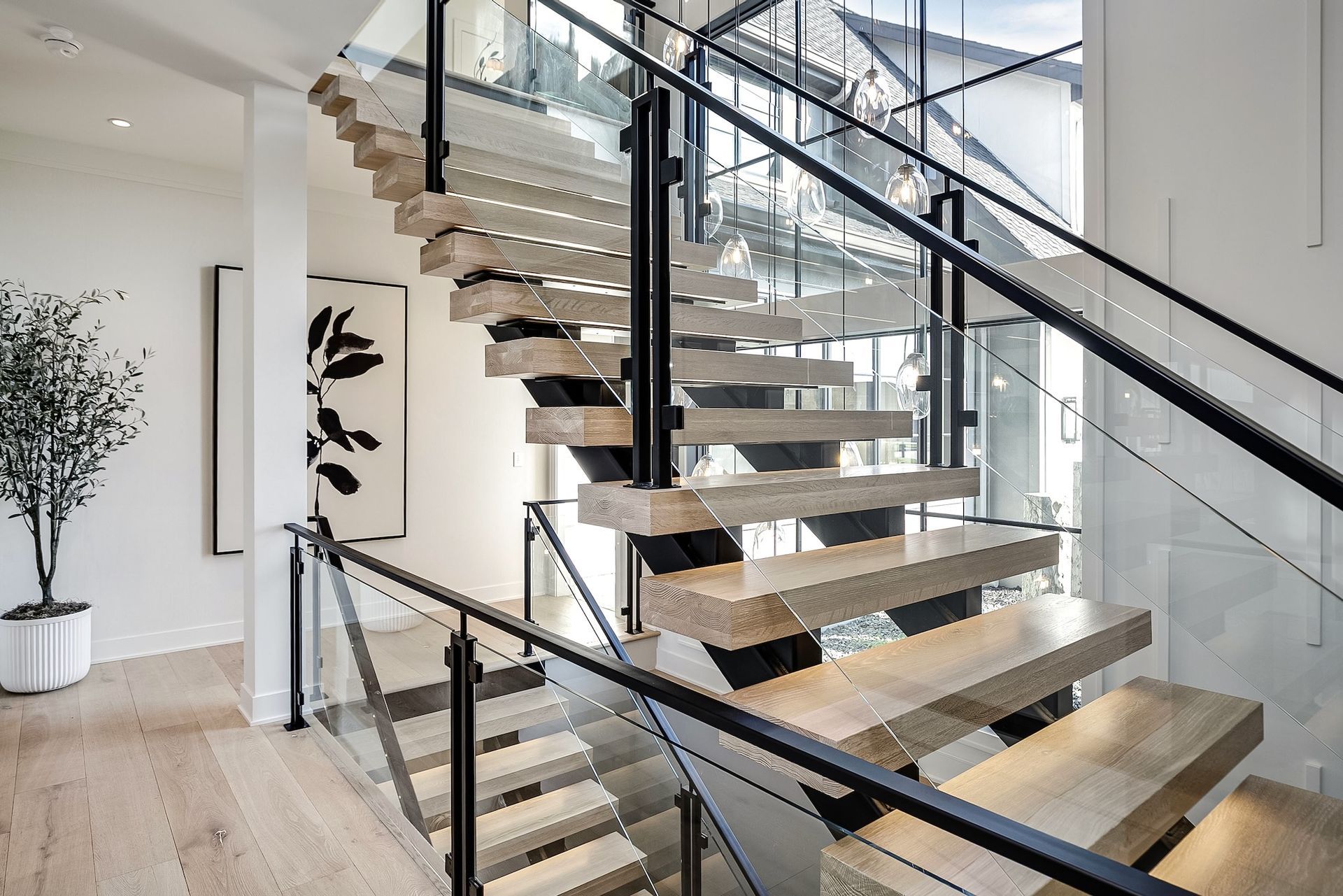 Modern indoor staircase with glass railings and wood steps in a bright, minimalist home
