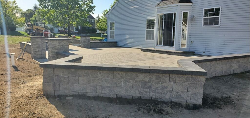 Cozy backyard seating area with stone path, fountain, flower pots, and wooden fence.