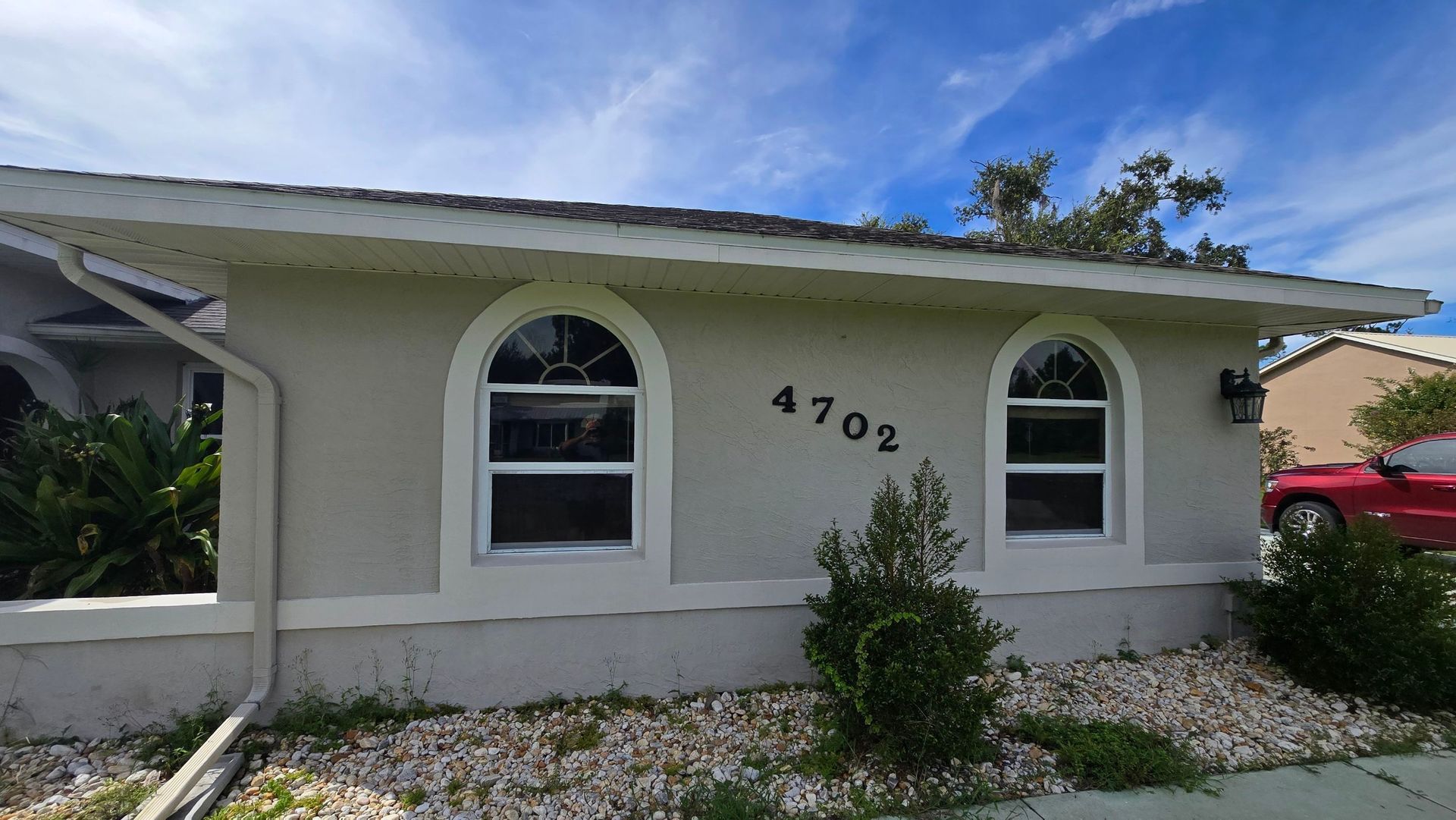 A light beige house with two arched windows, number 