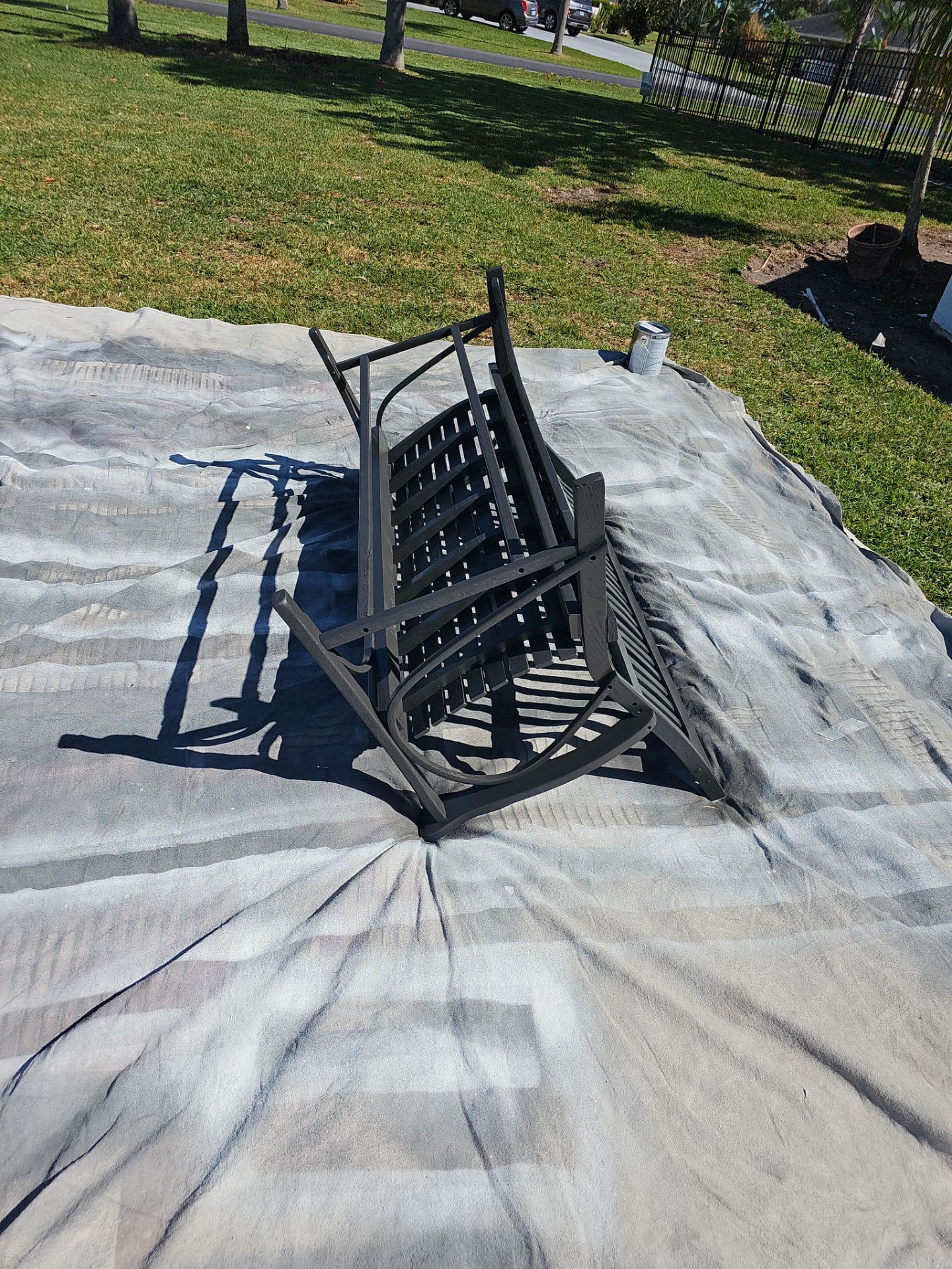 Black rocking bench on a tarp outdoors.