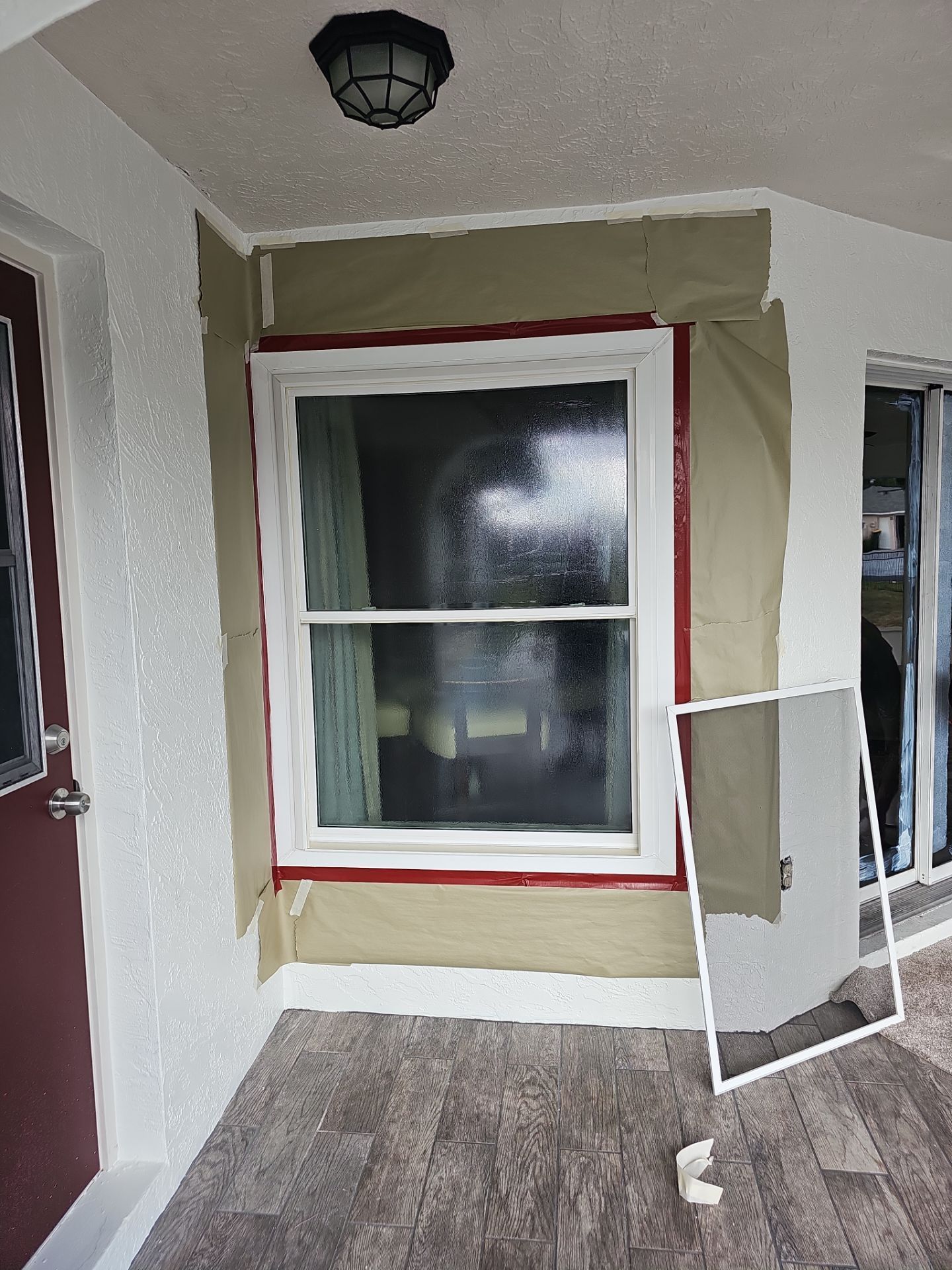Window installation: Exterior view with new window, masking tape, green wrap, and screen.