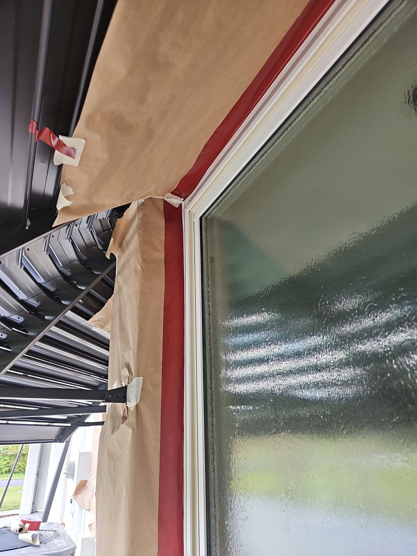 Red tape protects window frame during painting, masking off the white trim.