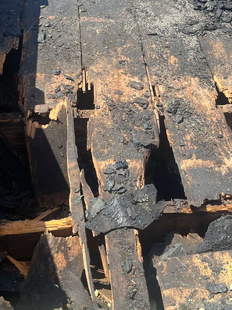 Charred wooden deck boards damaged by fire.