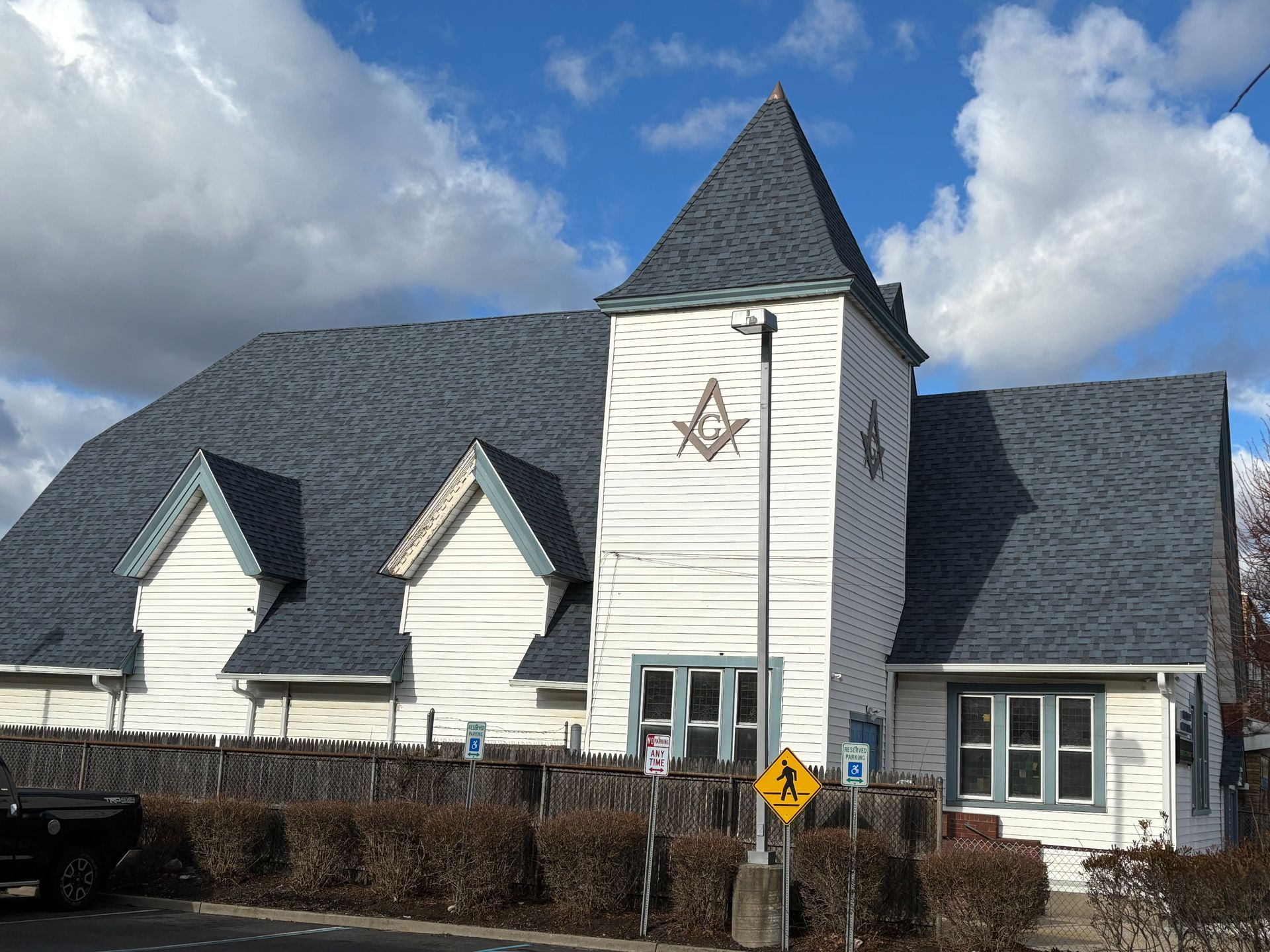 White Masonic lodge building with blue trim, gray roof, and a symbol.