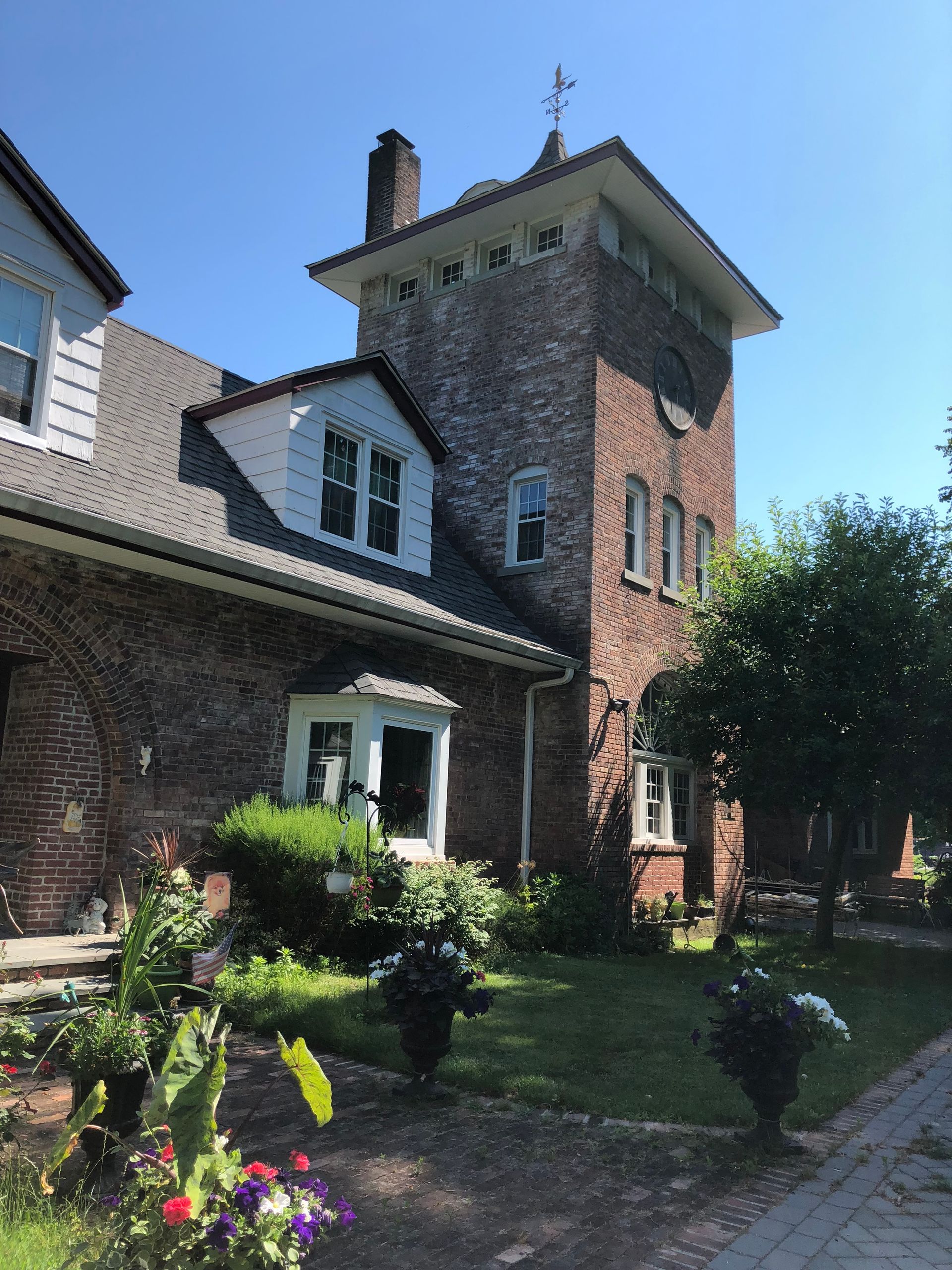 Brick house with tower, garden, and blue sky.
