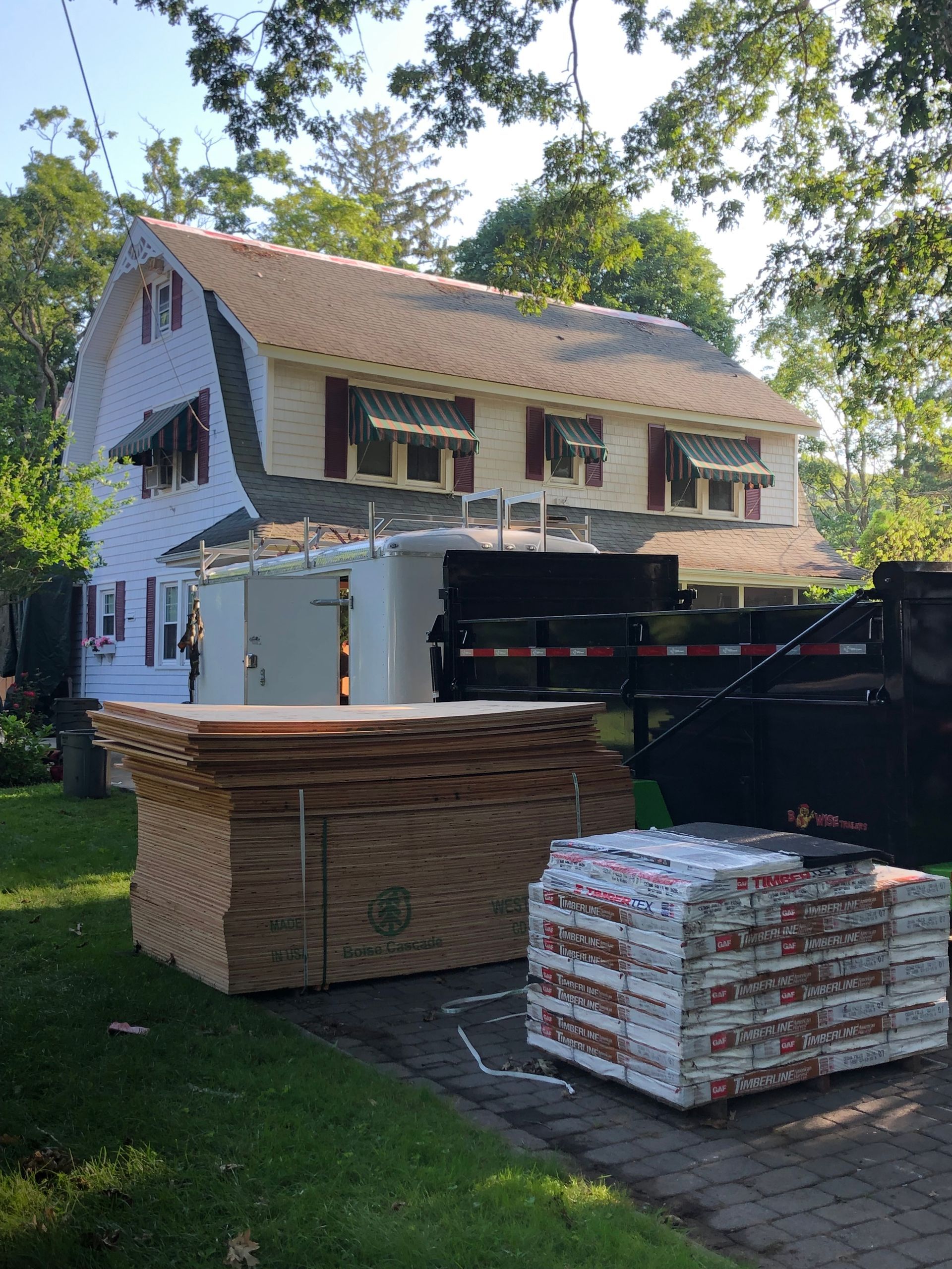Materials stacked near a Dutch Colonial house, likely for a roof replacement.