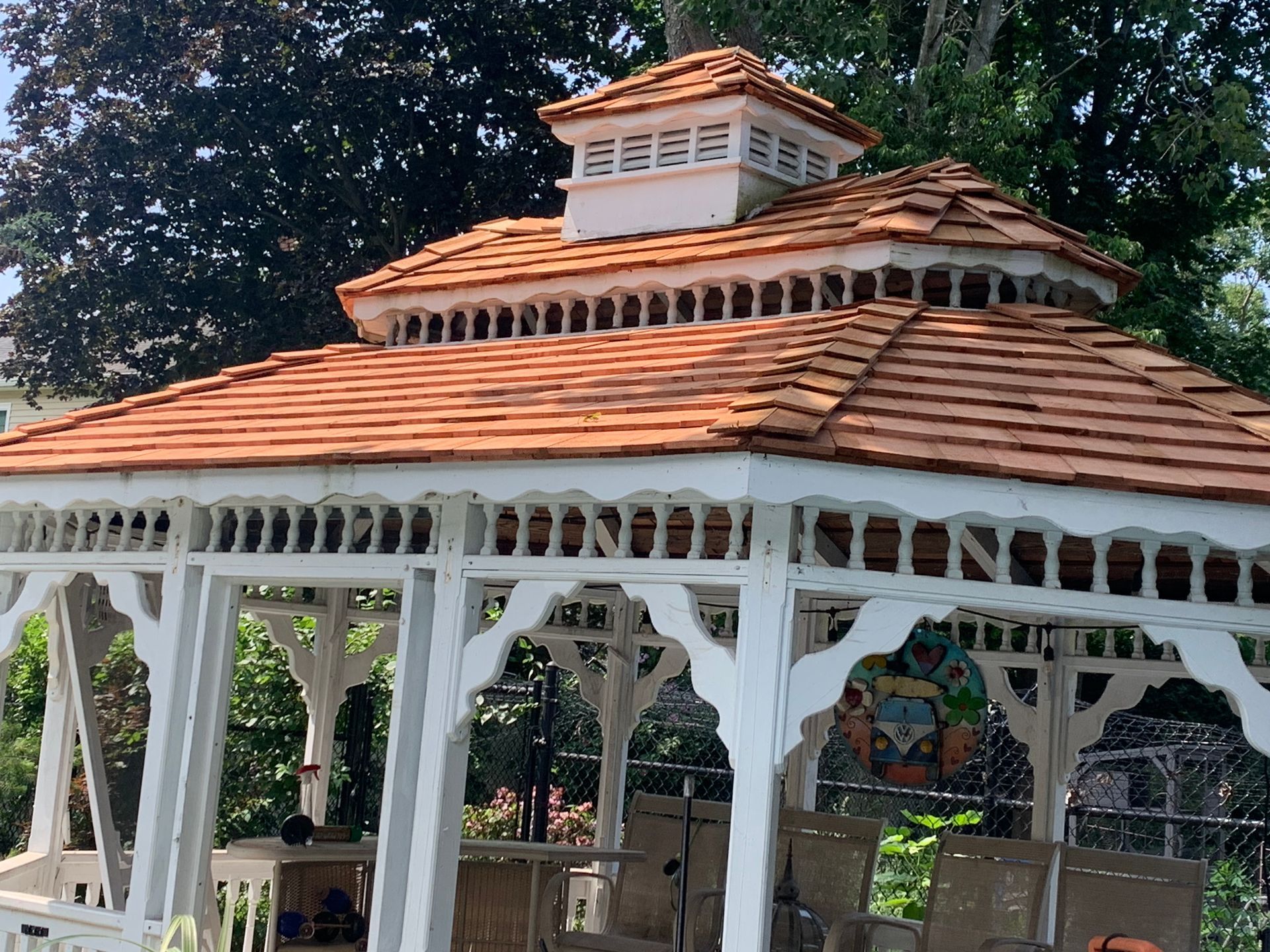 White gazebo with a reddish-brown shingled roof and a white cupola.