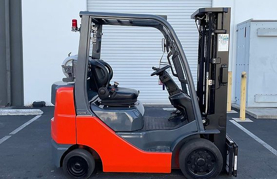A red and black forklift is parked in a parking lot.