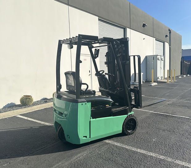 A green forklift is parked in a parking lot in front of a building.