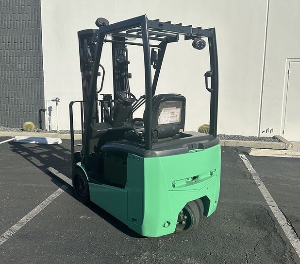 A green forklift is parked in a parking lot in front of a building.